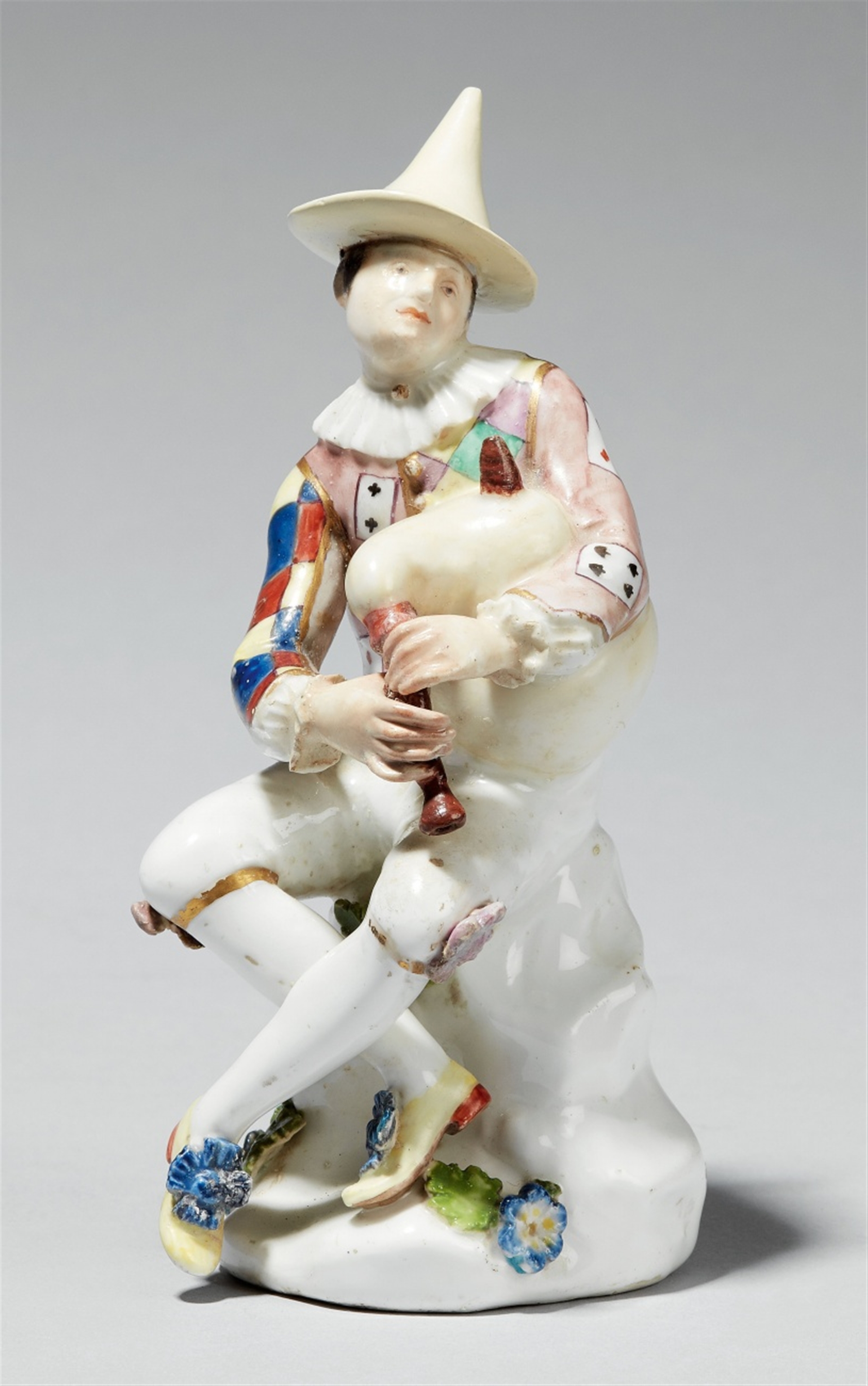 A Meissen porcelain figure of harlequin playing bagpipes ...