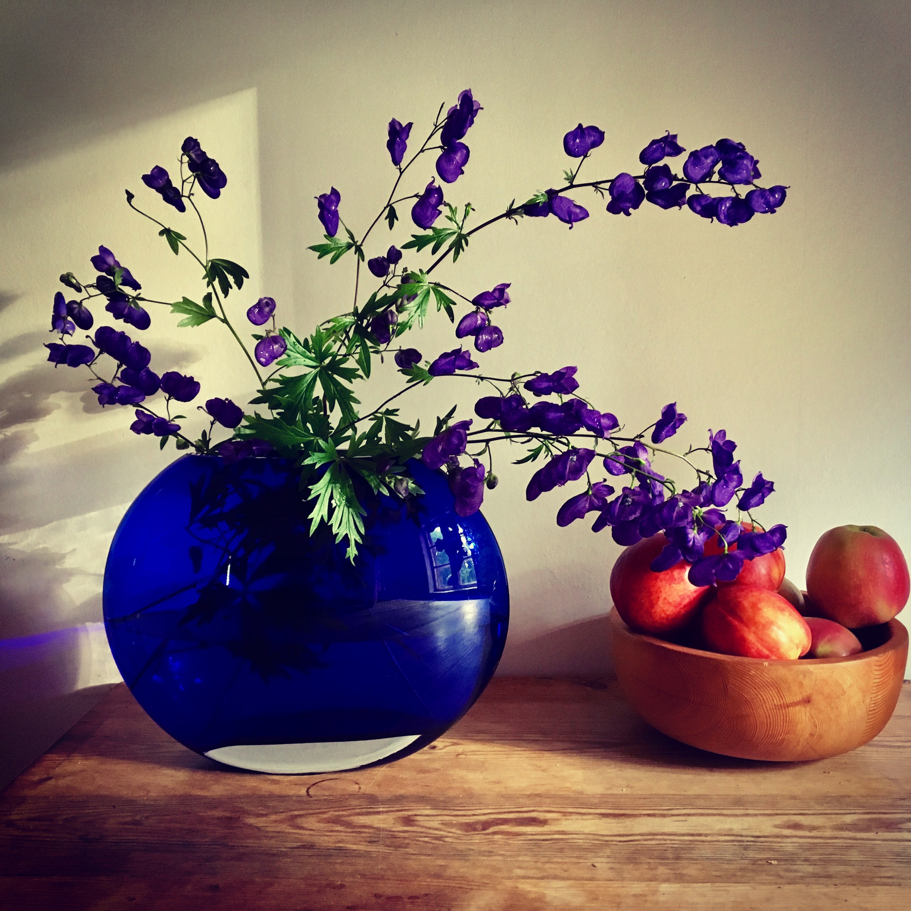 Purple petaled flower arrangement near apple fruit on table photo