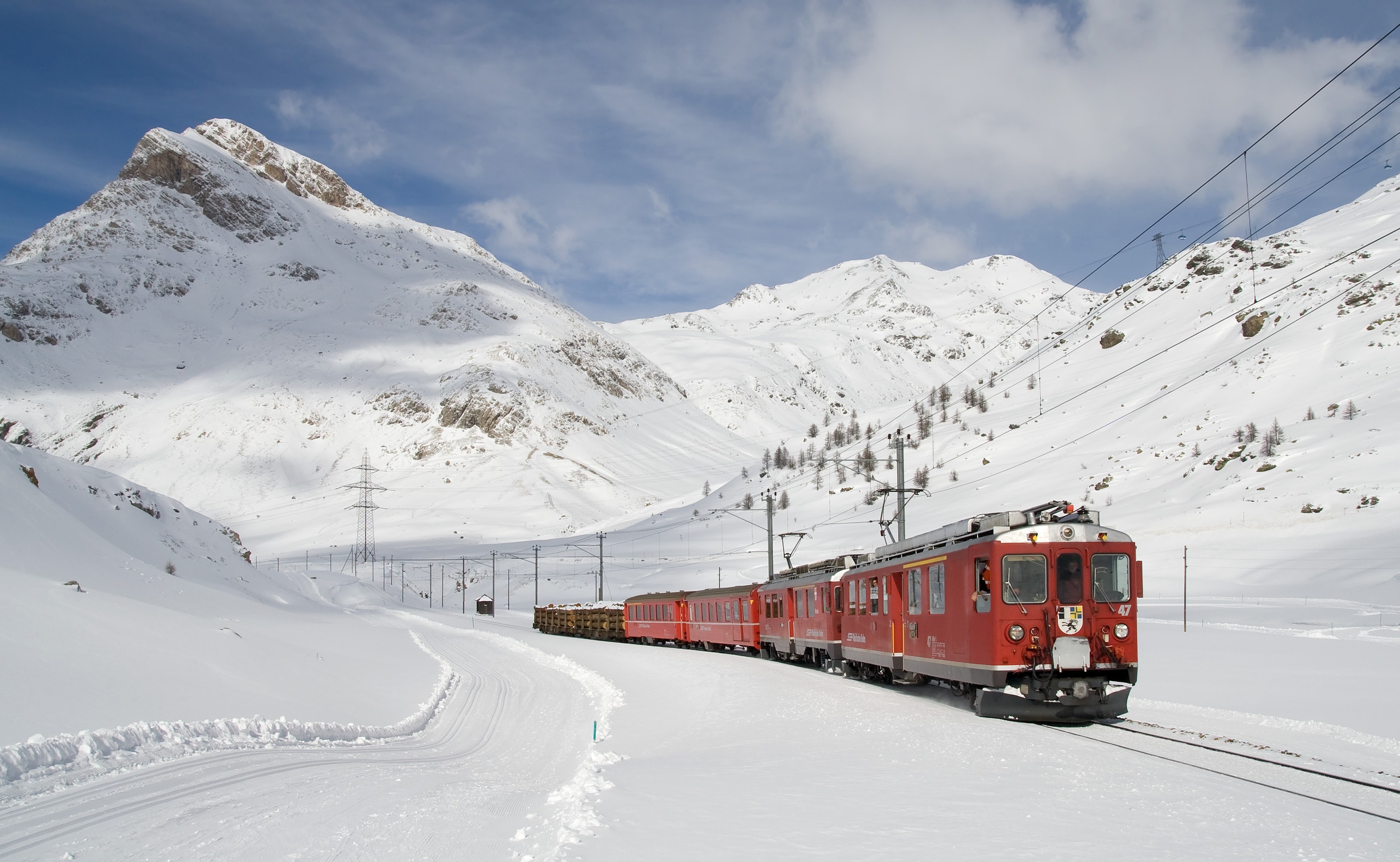 Red and black train running along snow covered field photo