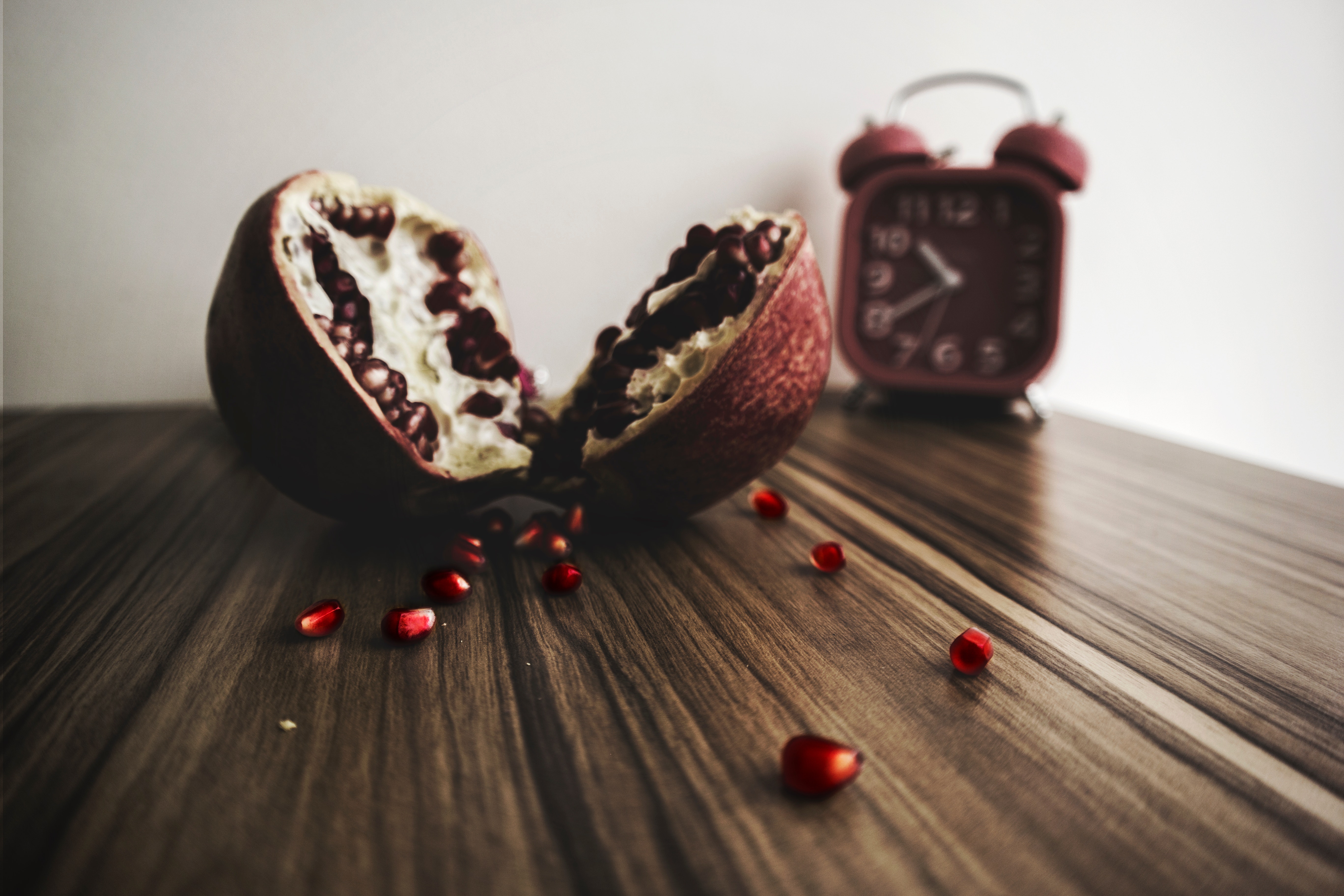 Red and white round fruit on brown wooden table with red alarm clock photo