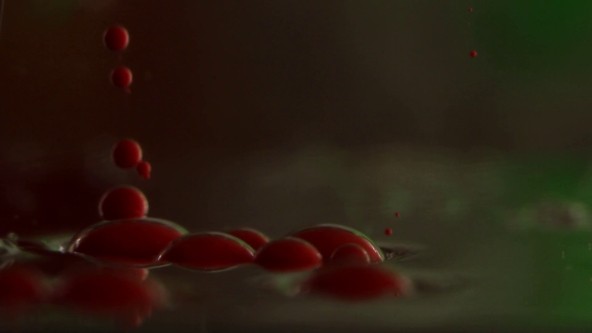 Closeup of opaque red bubbles falling quickly and drifting down ...