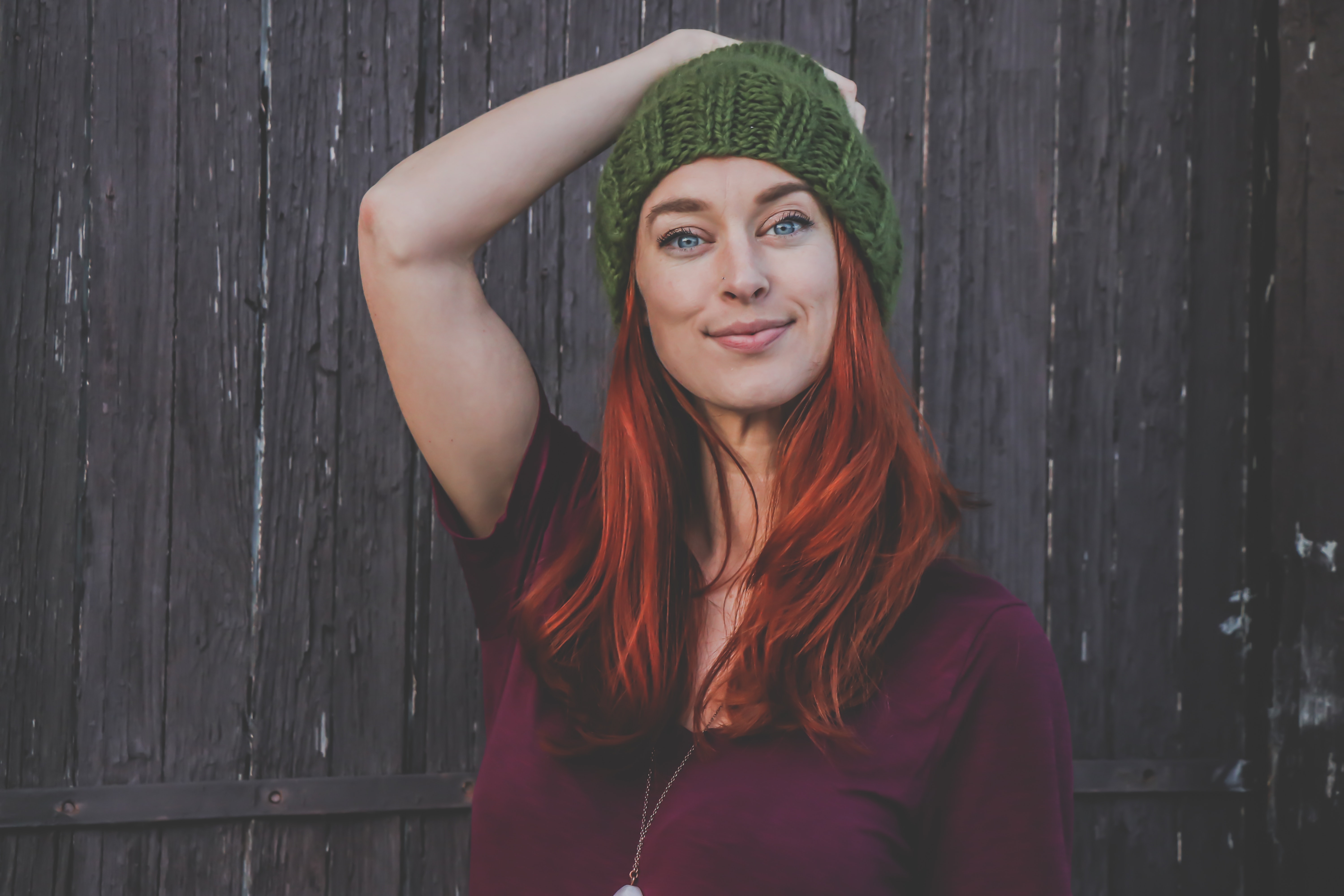 Red haired woman in maroon top wearing green beanie photo