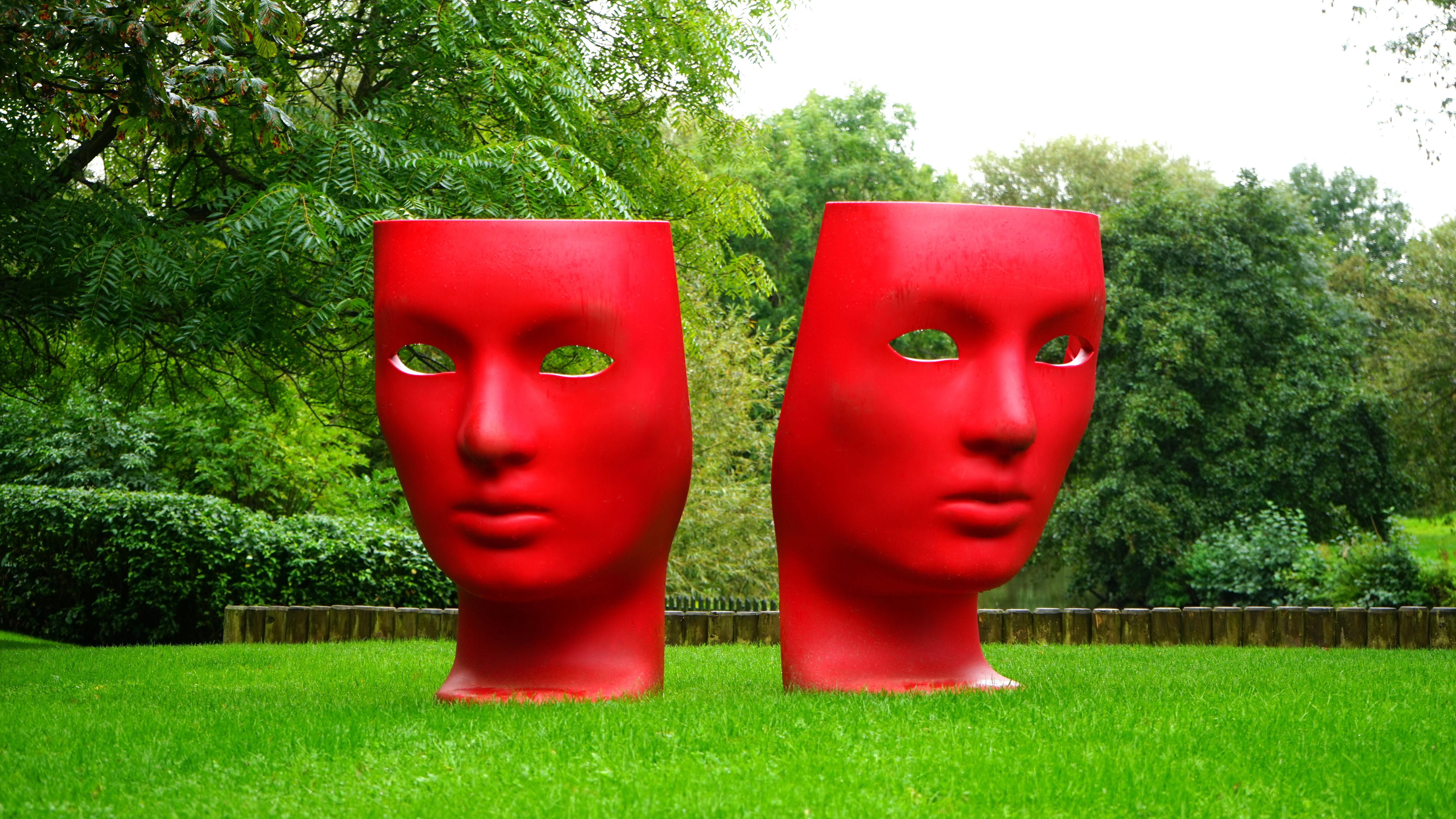 Red human face monument on green grass field photo