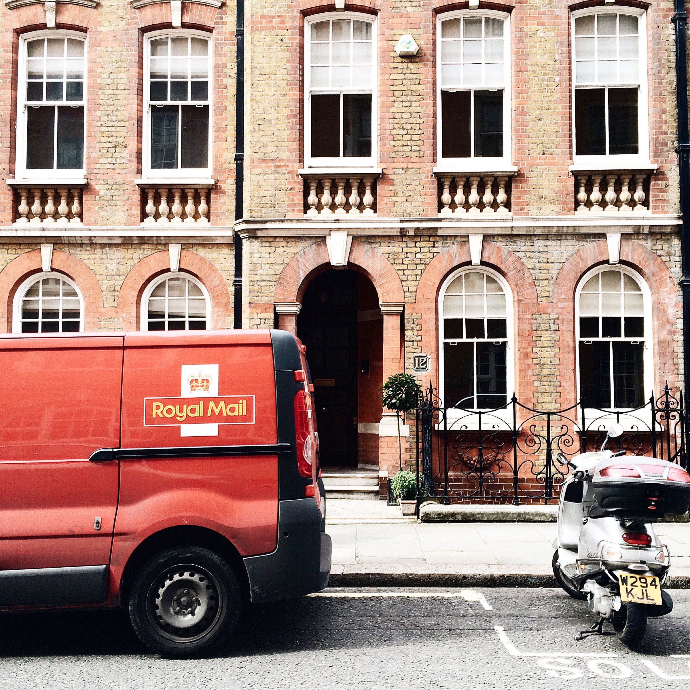 Red royal mail parked near brown brick building photo