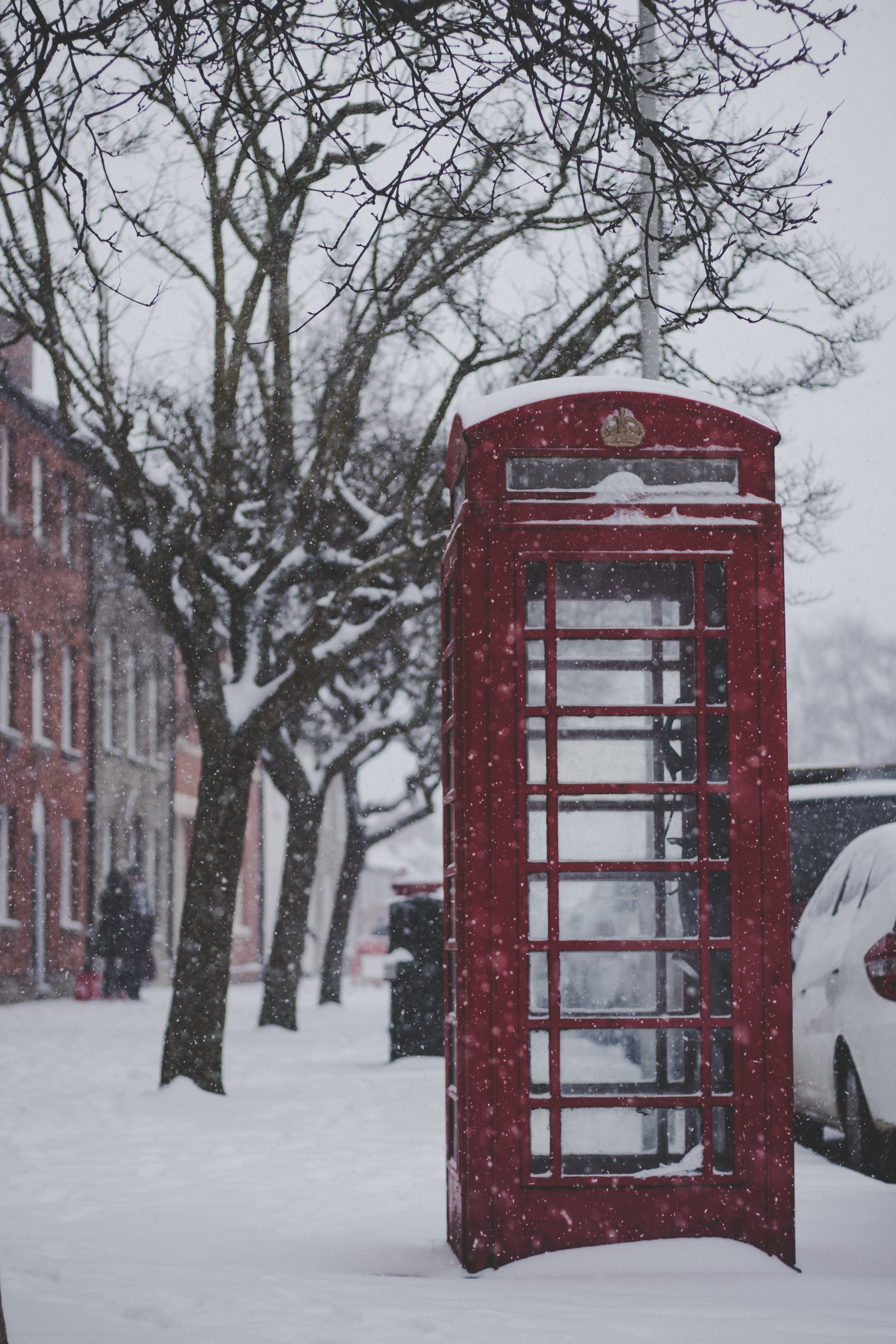 Red telephone booth on the sidewalk with snow photo