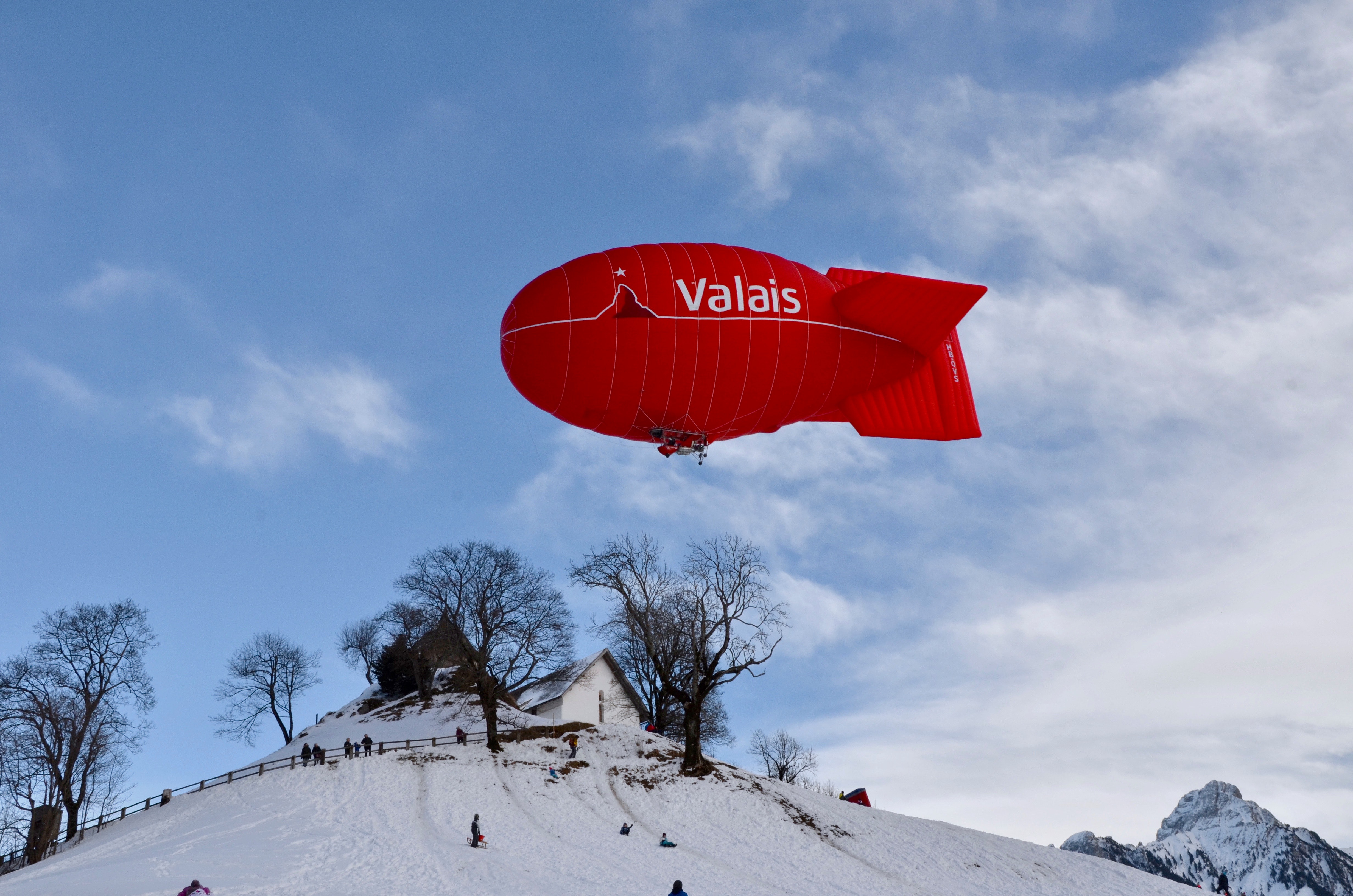 Red valais blimp above white wooden house photo