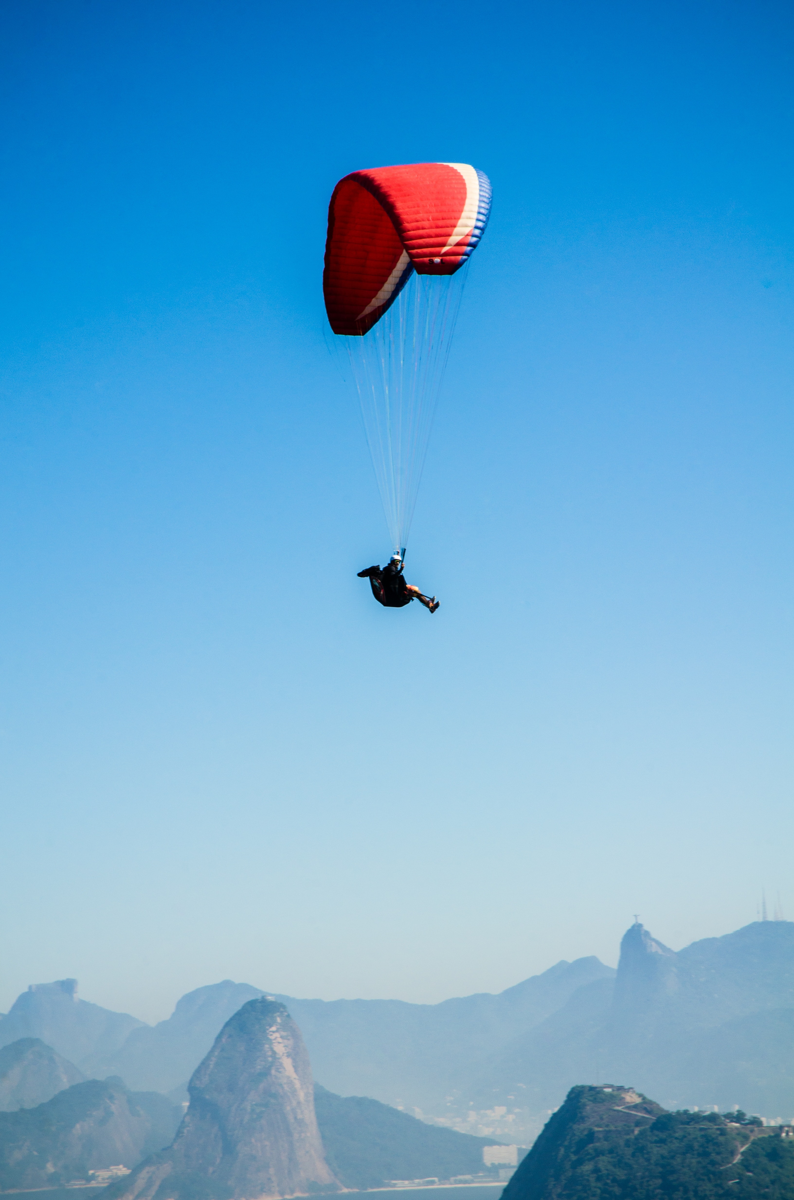 Red white parachute on top of mountains during daytime photo