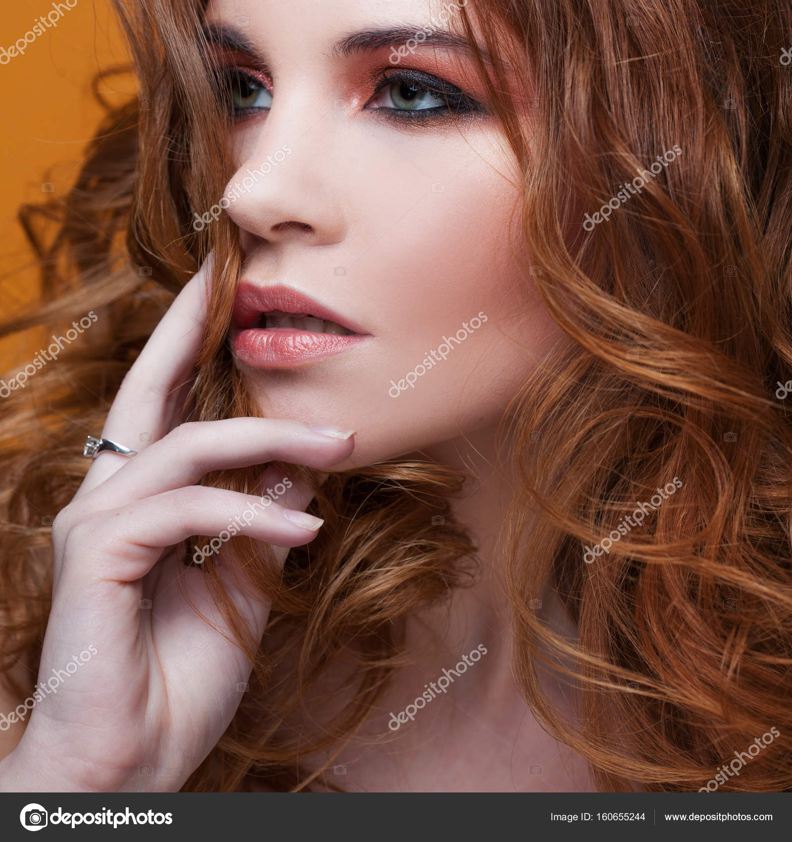 Beautiful redheaded girl with luxurious curly hair. Studio portrait ...