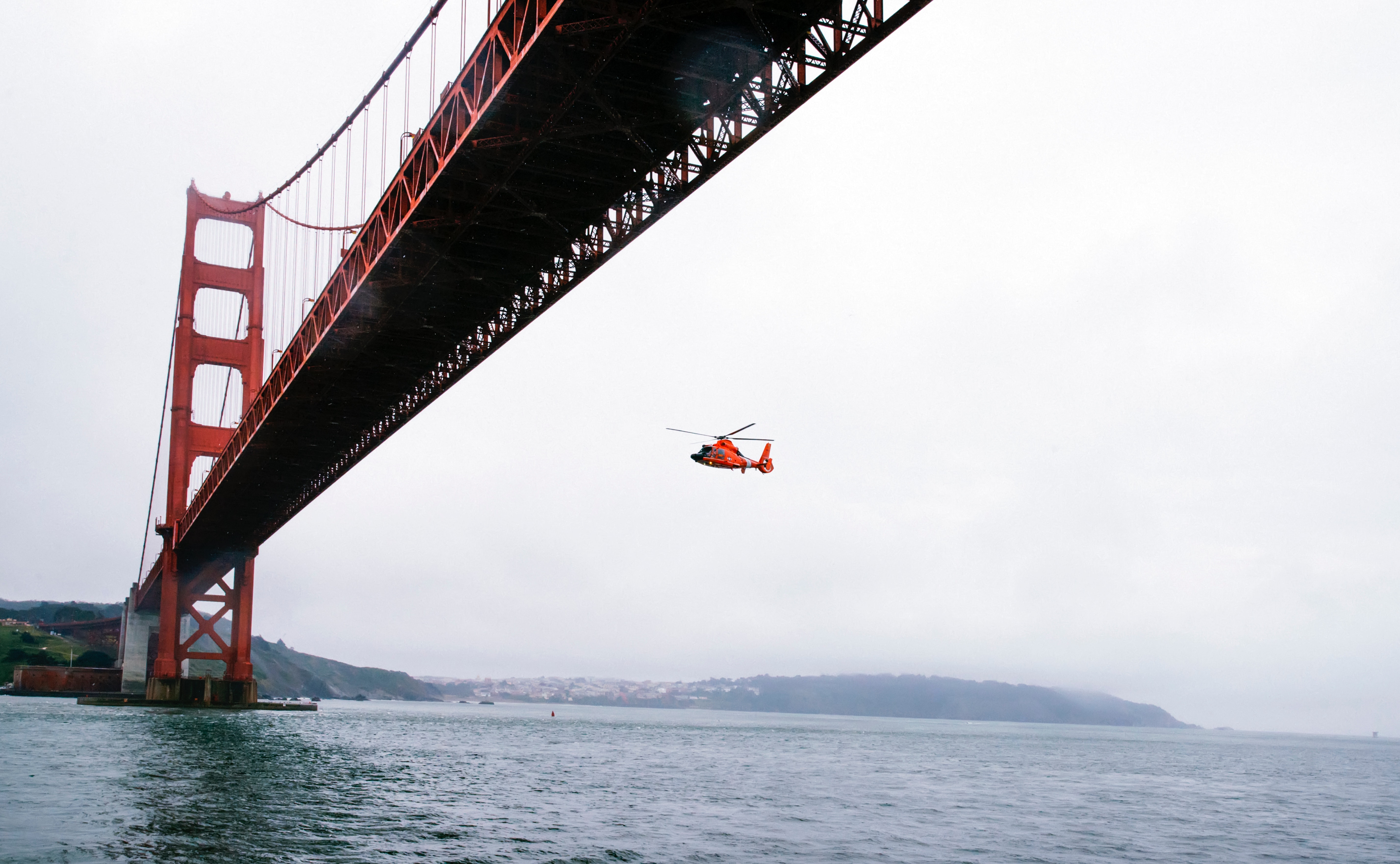 Rescue helicopter flying under golden gate bridge photo