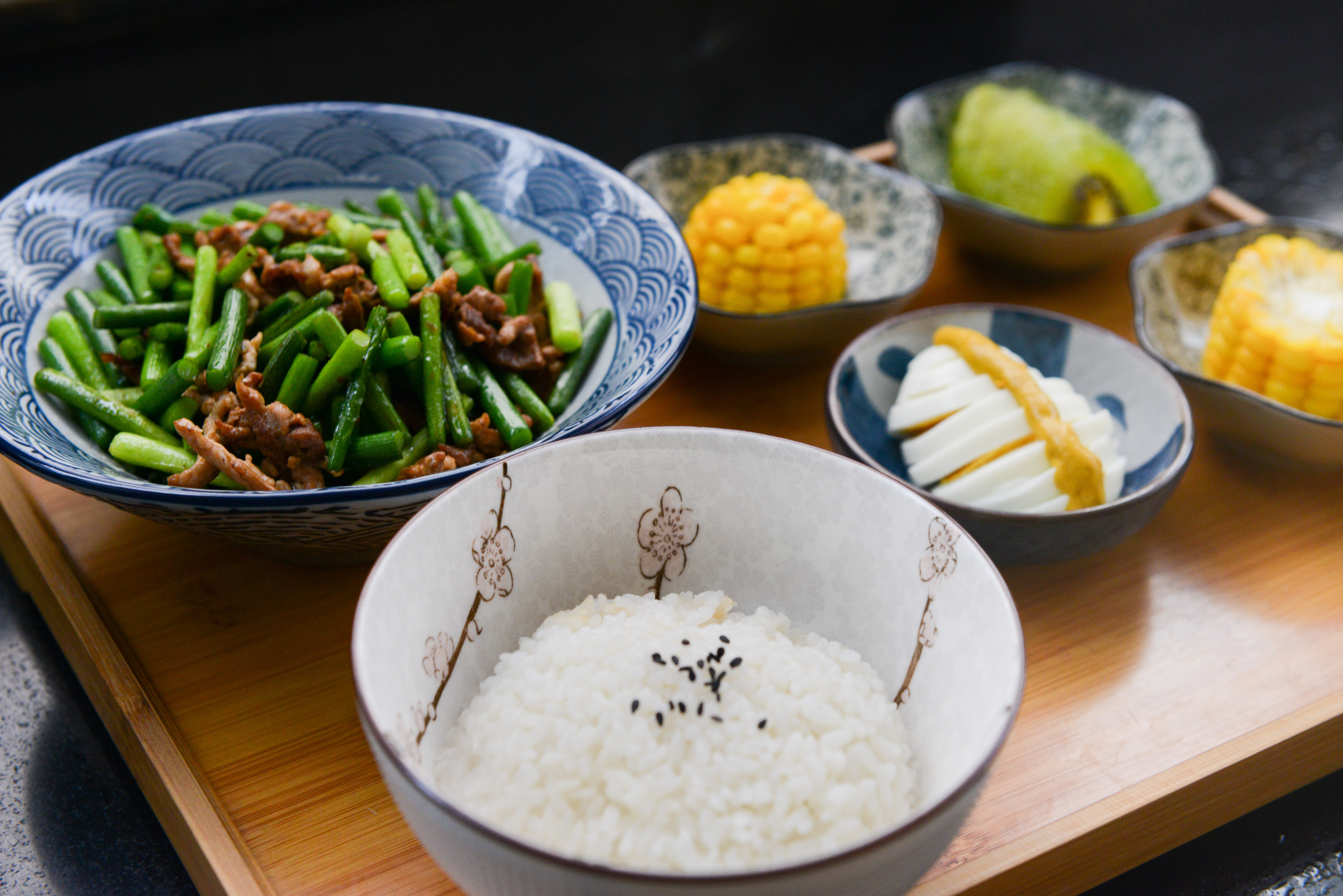 Rice on bowl, sliced-egg, corn, and vegetable on table photo