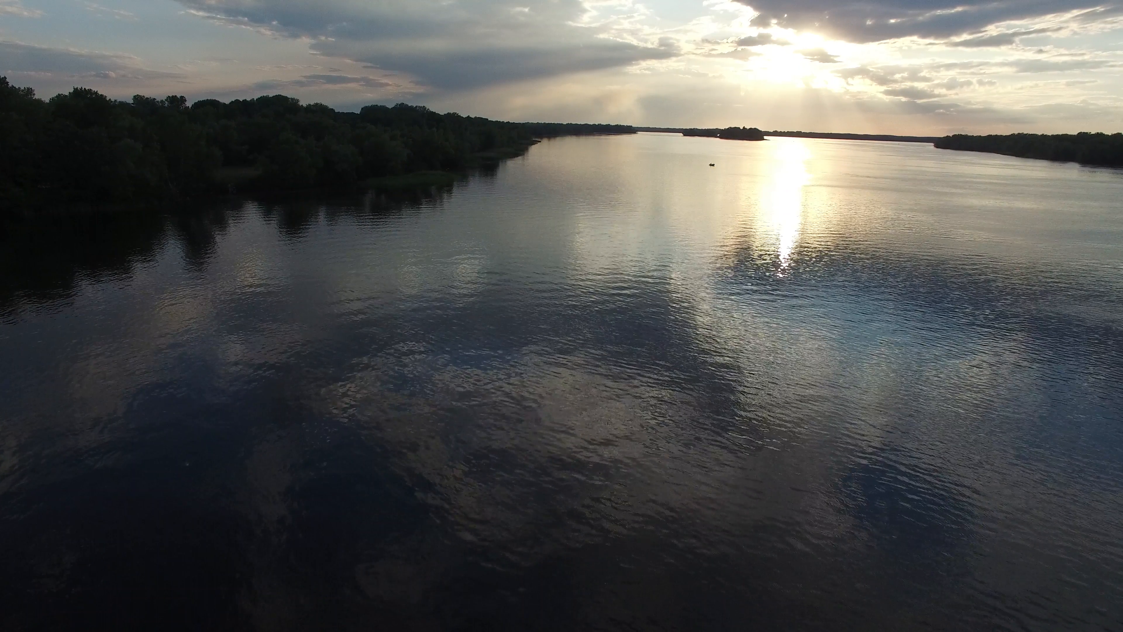 Aerial view, flight backward. Big river during sunset. Sun rays in ...