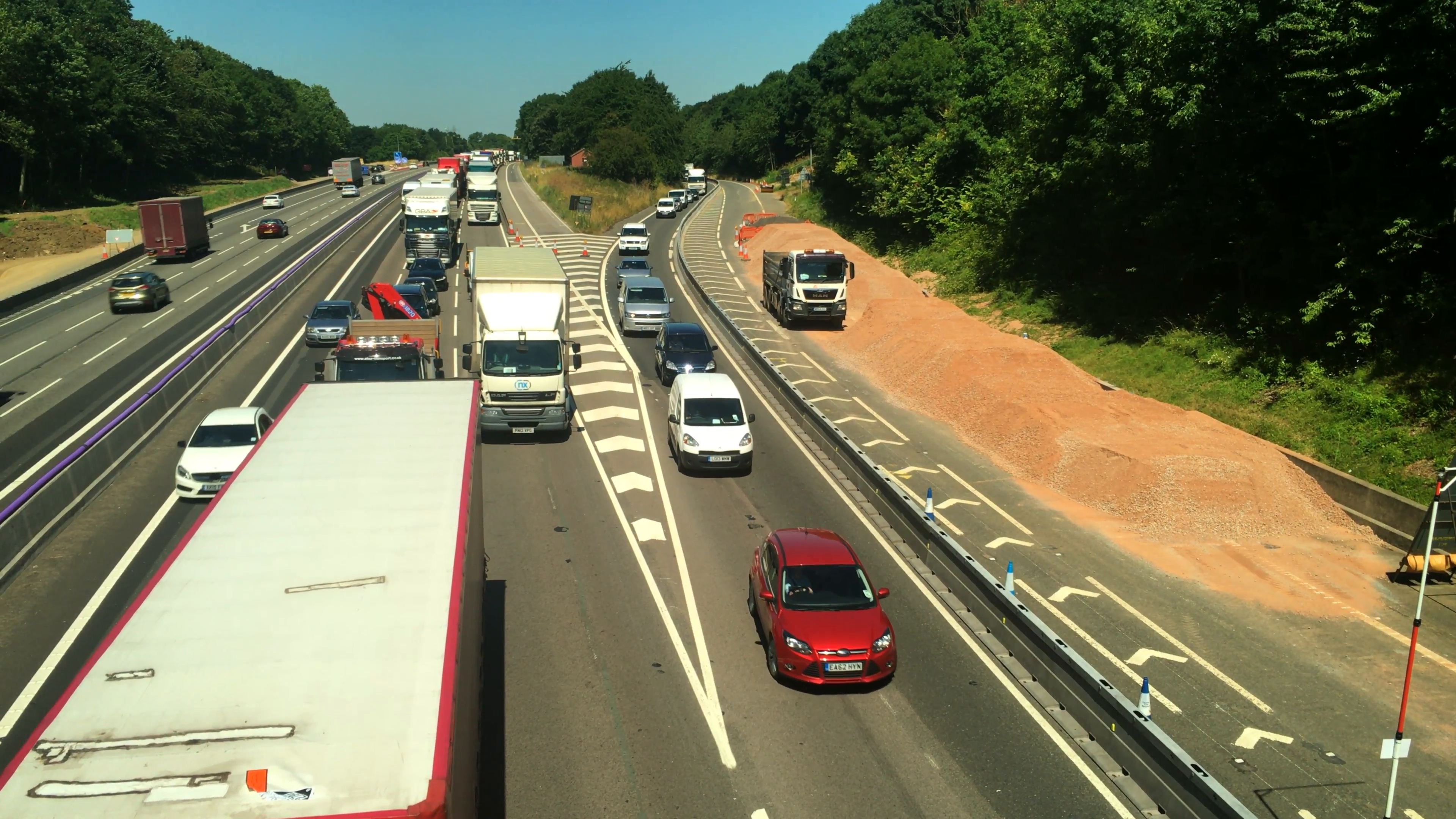 Pan over an almost stationary road traffic queue at road works on ...