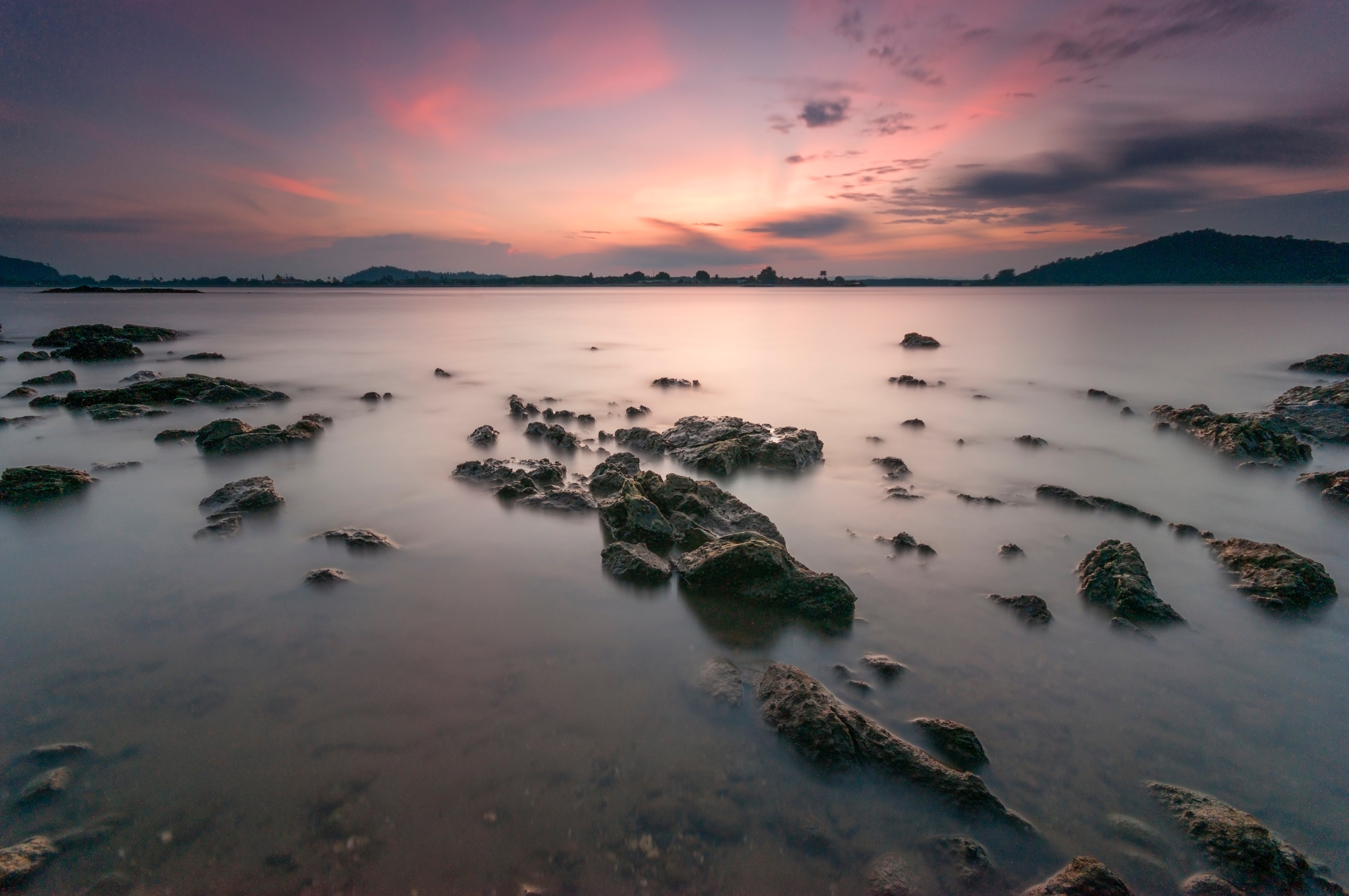 Rocks on body of water during sunset photo