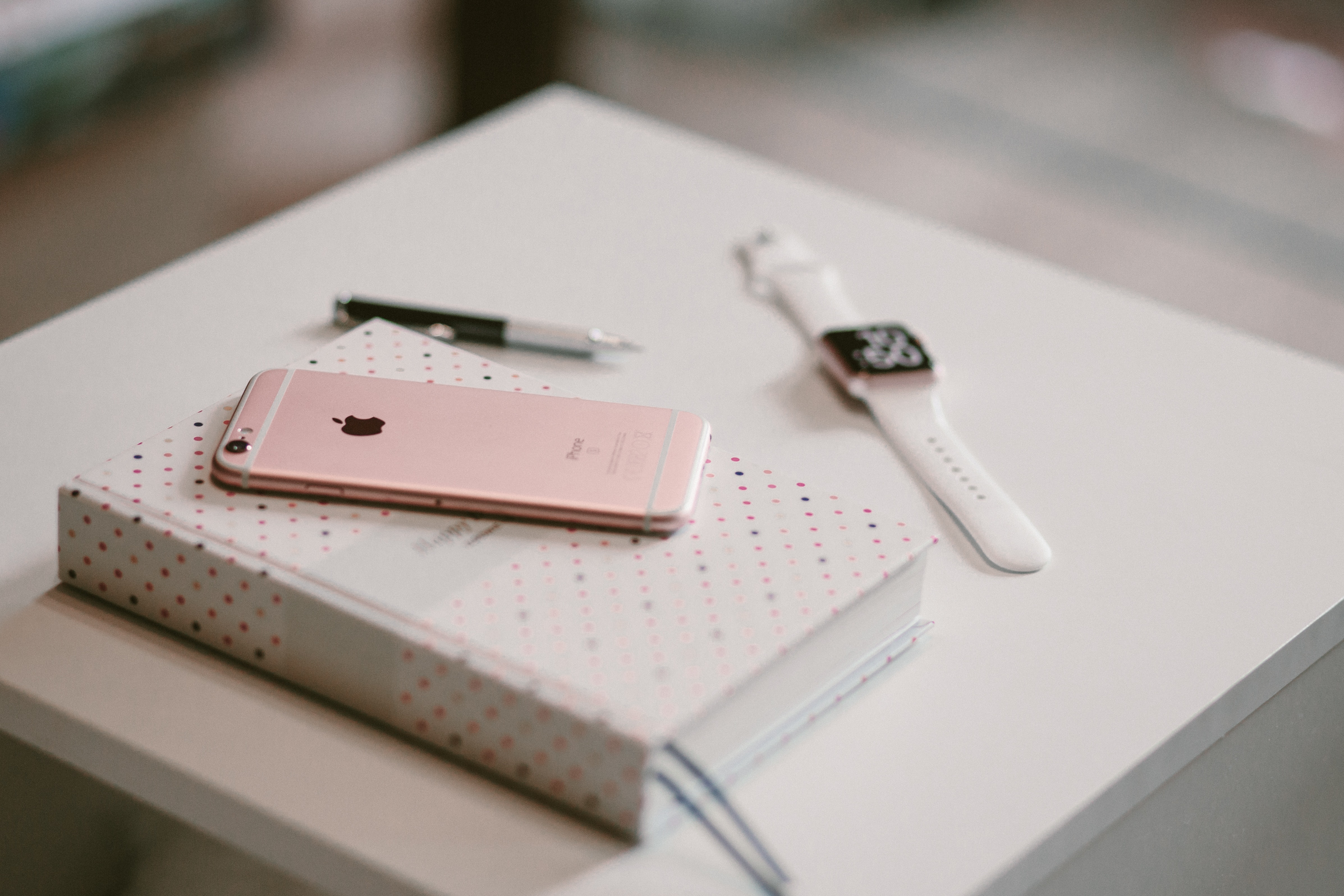 Rose gold iphone 6 s on top of white covered book photo