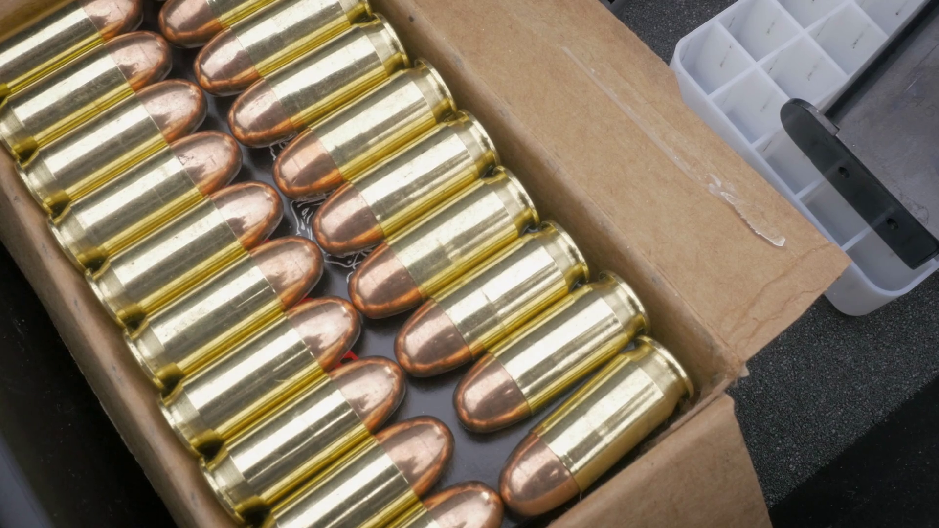 Push in towards a full box of 9mm bullets. The brass and copper ...