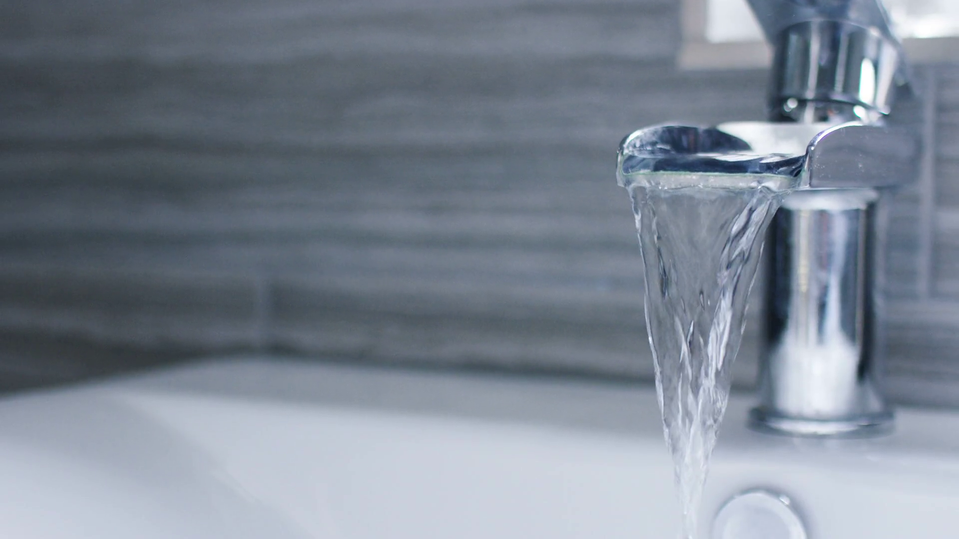 Running water from a waterfall tap in a bathroom, in slow motion ...