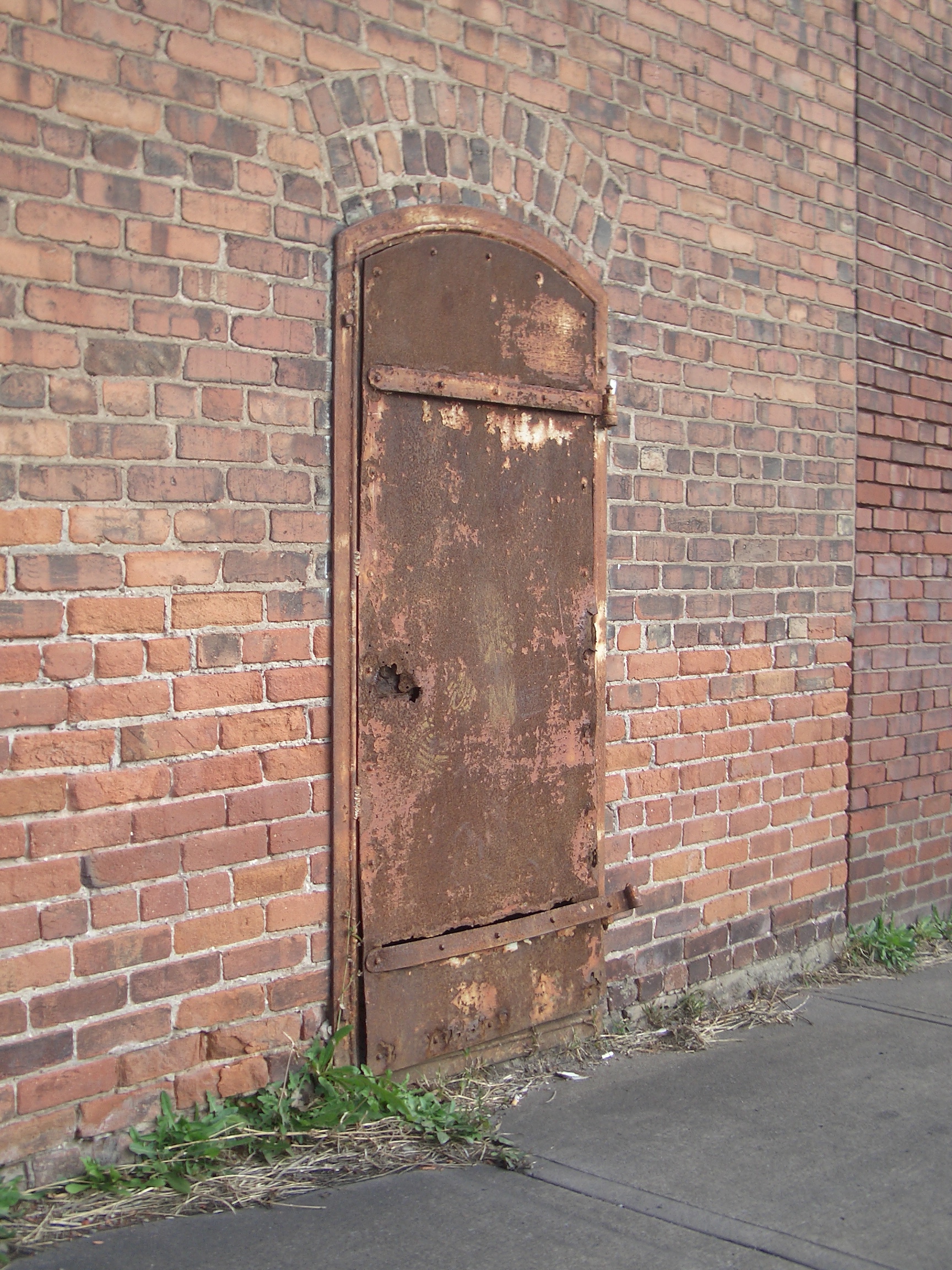 Rusty metal door in a brick wall [image 1728x2304 pixels]