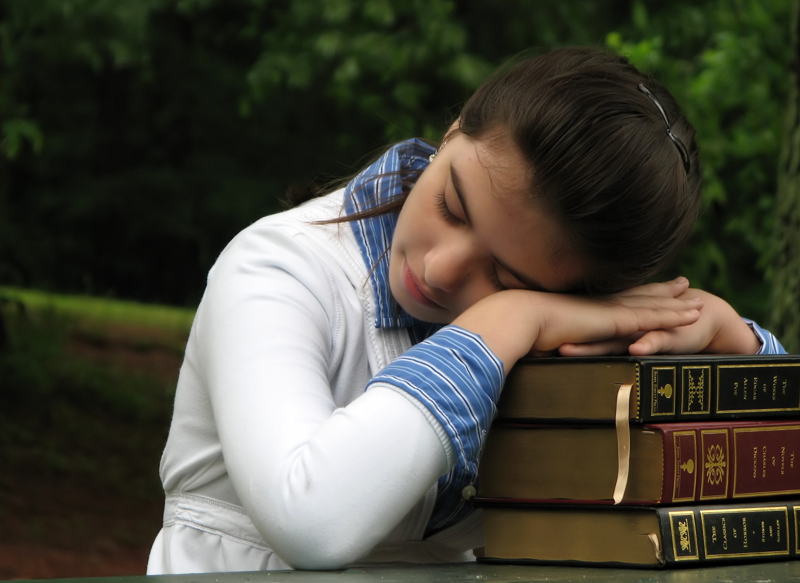 Schoolgirl resting her head on books photo