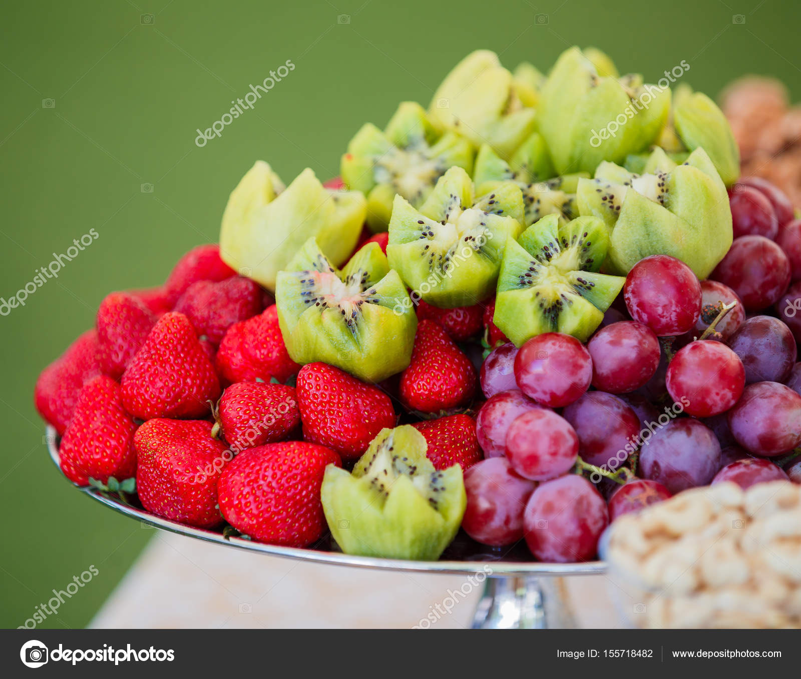 Fresh fruits on plate. Strawberries, kiwi, grapes and cashew nuts on ...