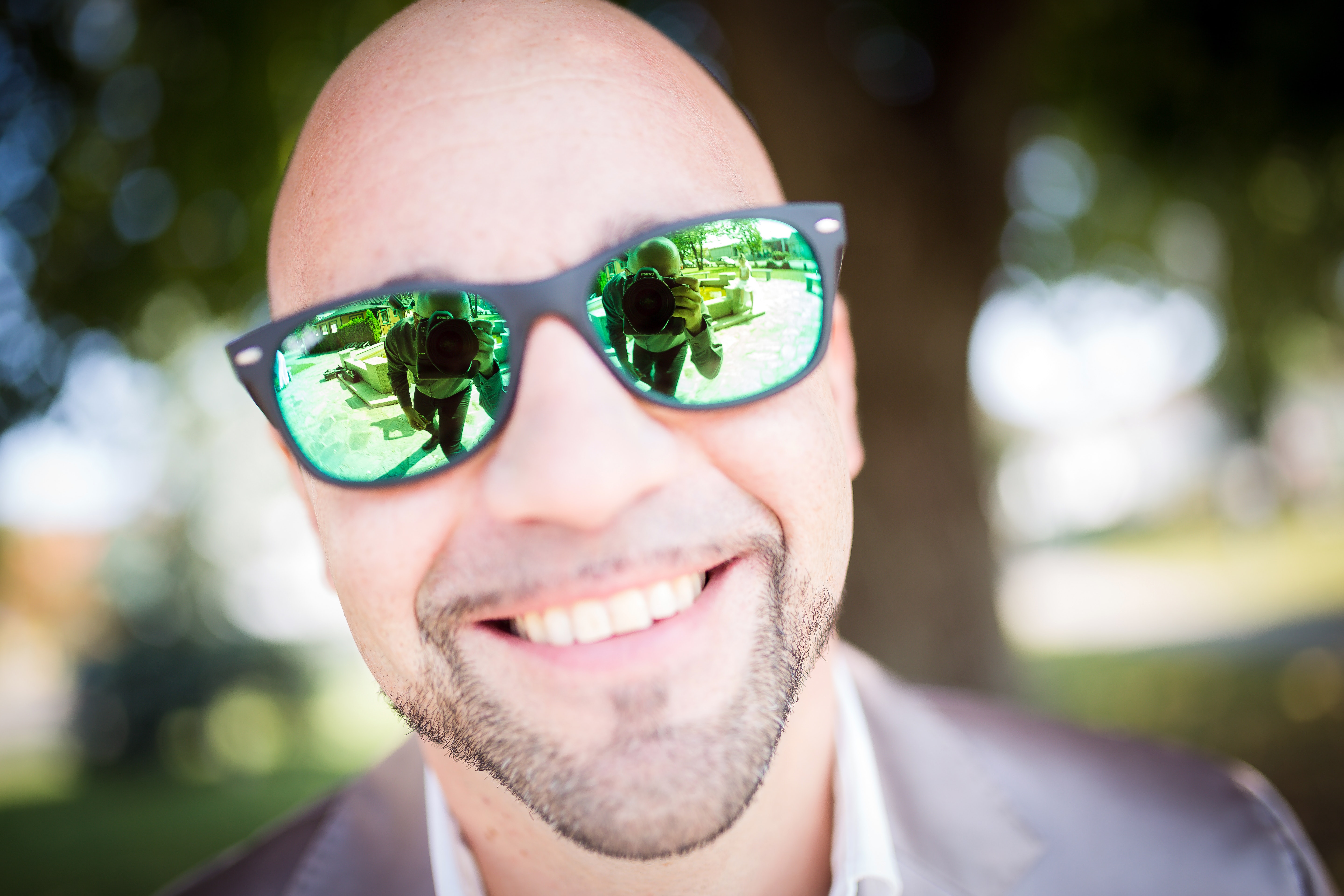 Shallow focus photography of man in gray top wearing green sunglasses with black frames