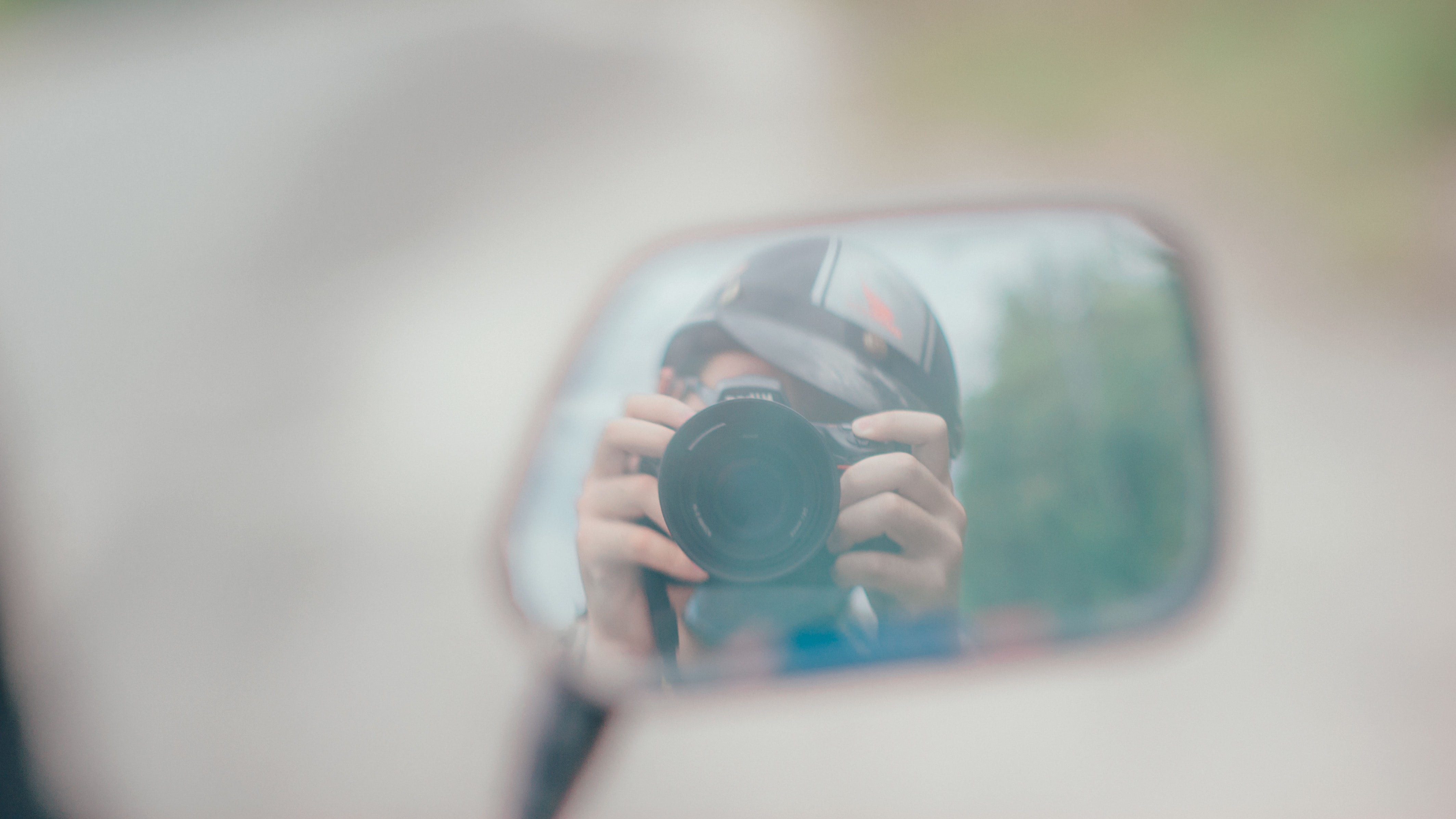 Shallow focus photography of person holding dslr camera in mirror reflection