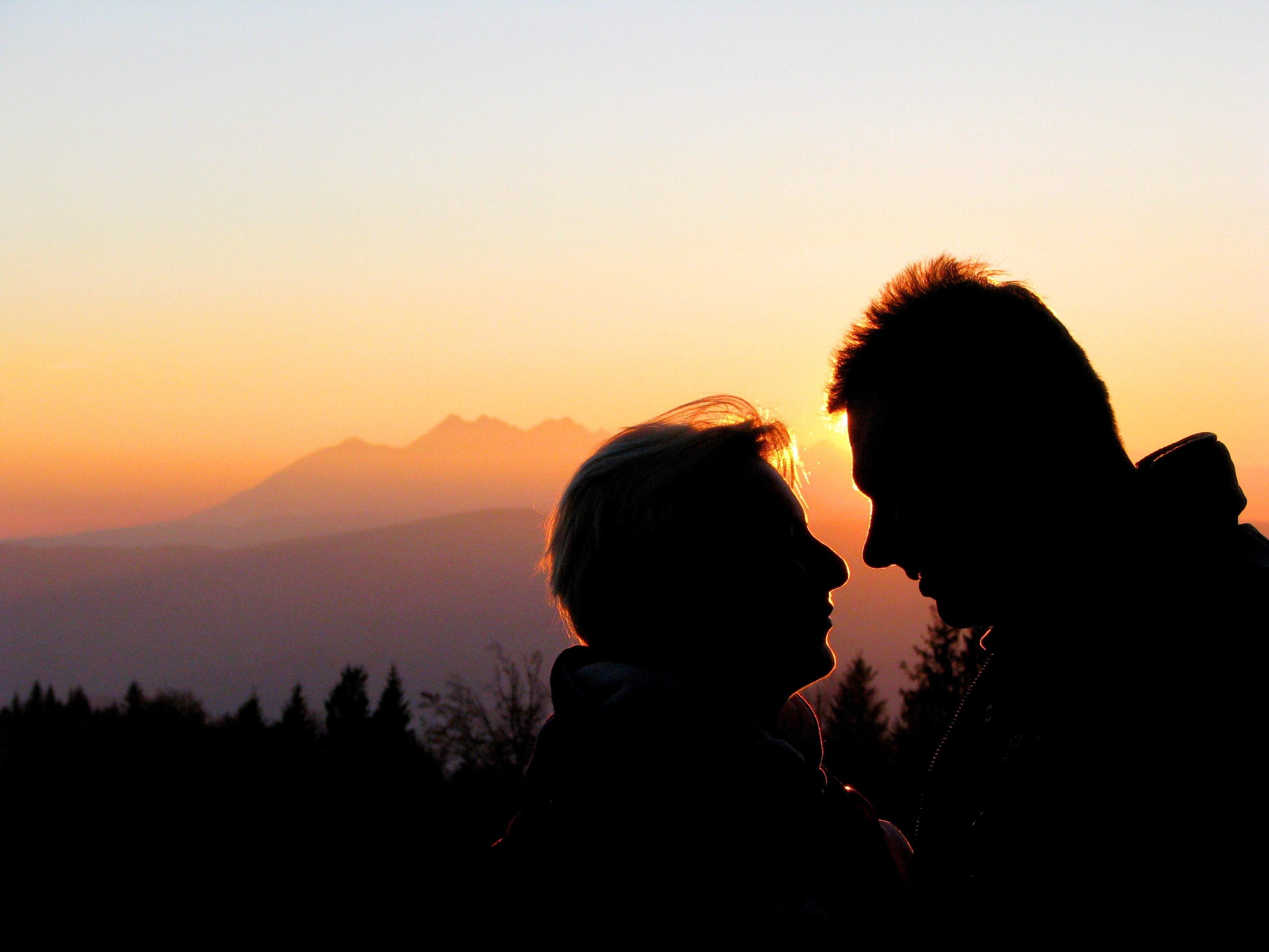 Silhouette couple kissing against sky during sunset photo