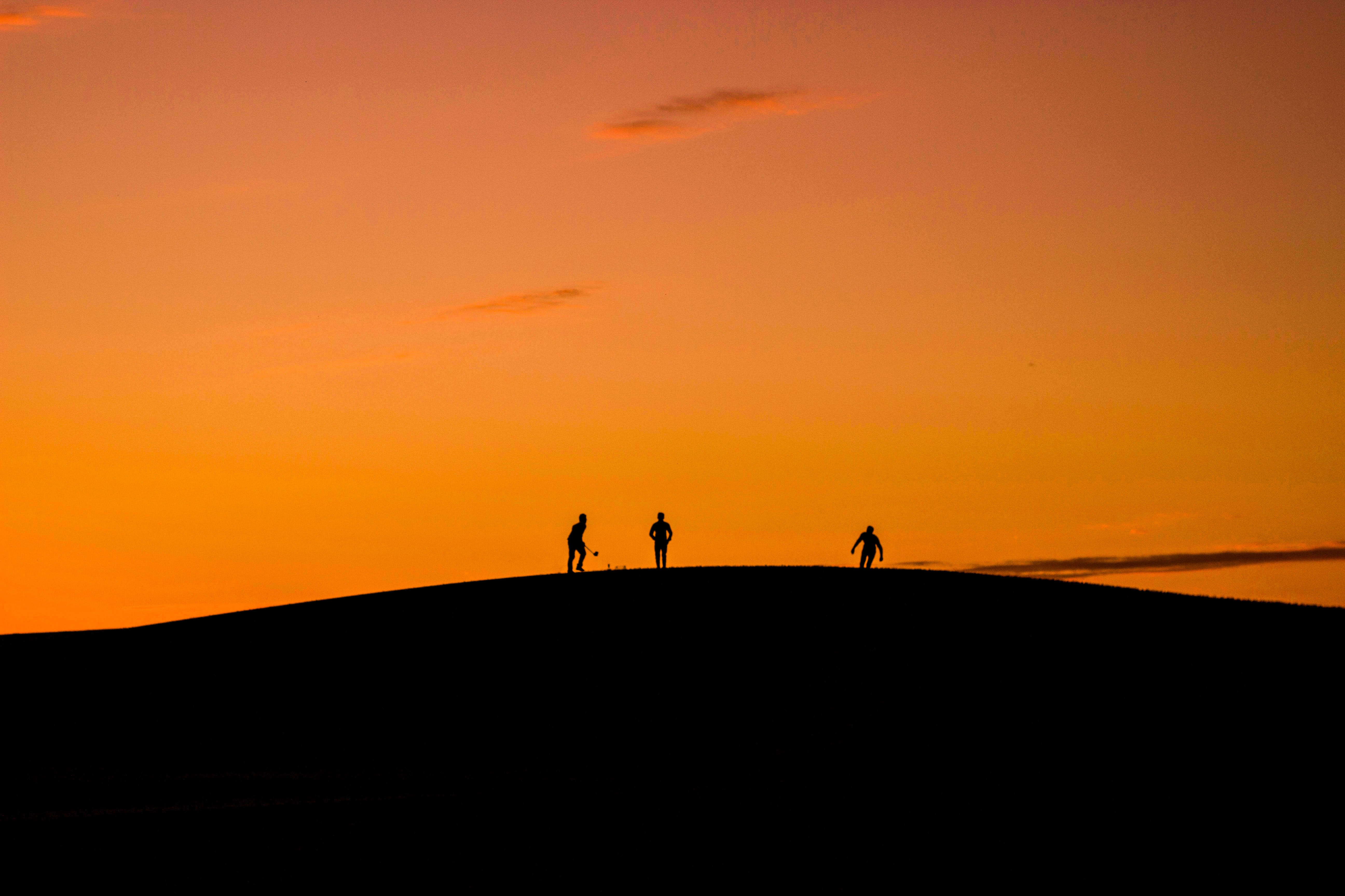Silhouette of 3 people in hill during sunset photo