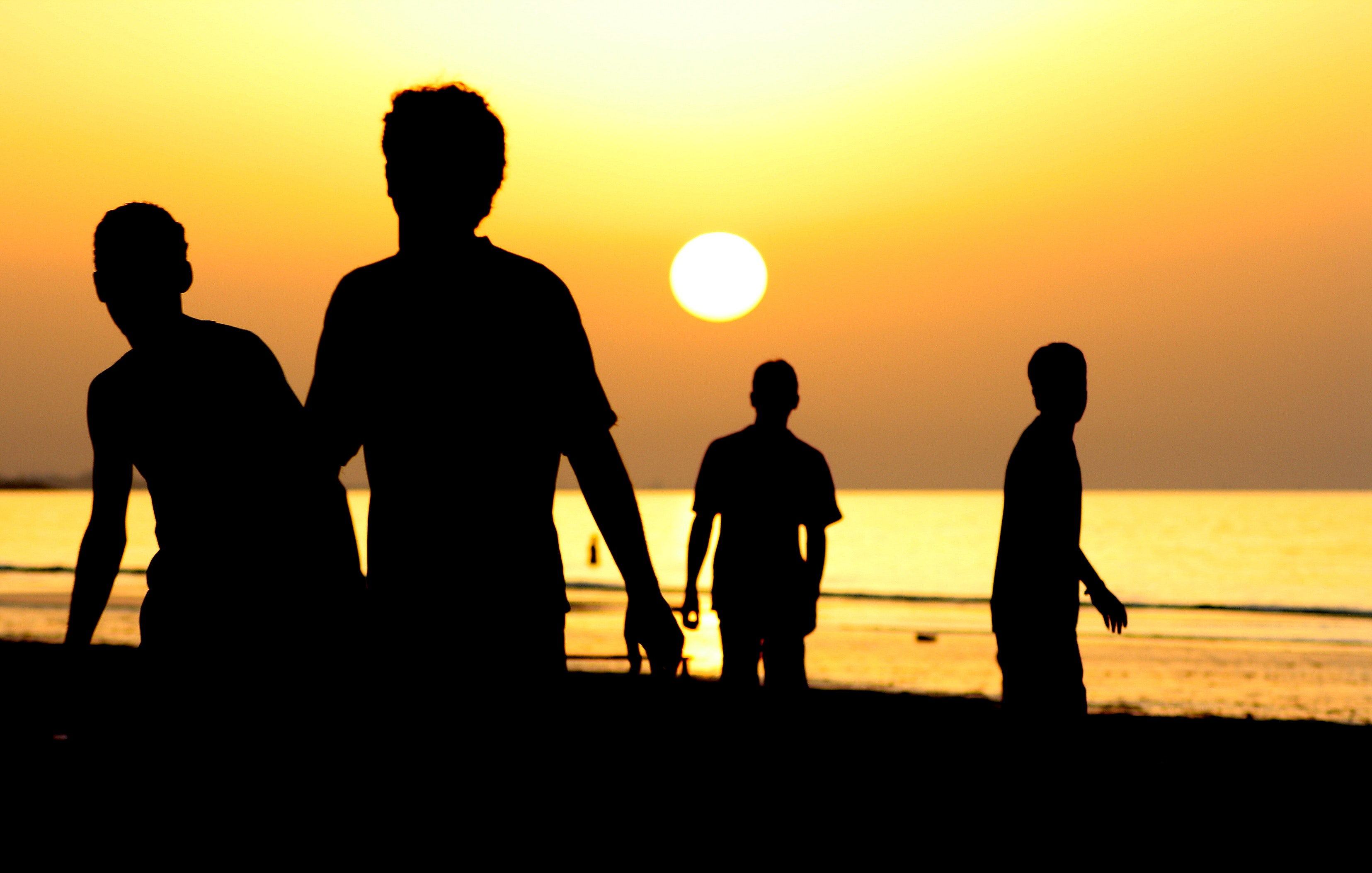 Silhouette of 4 people near ocean during sunset photo
