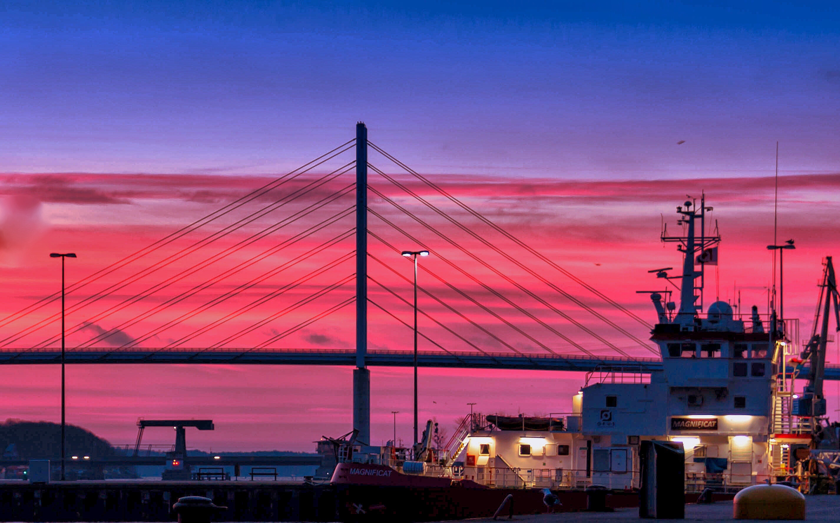 Silhouette of a bridge under red clouds and blue sky taken during night time photo