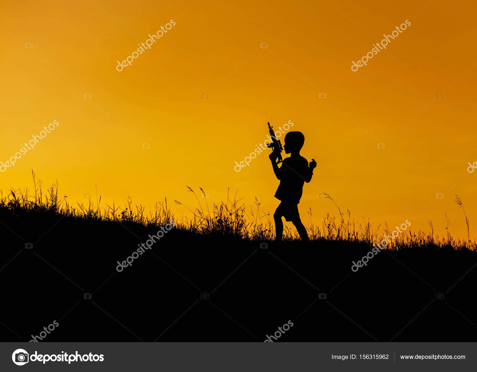 silhouette little boy hold toy machine gun playing on sunset on the ...