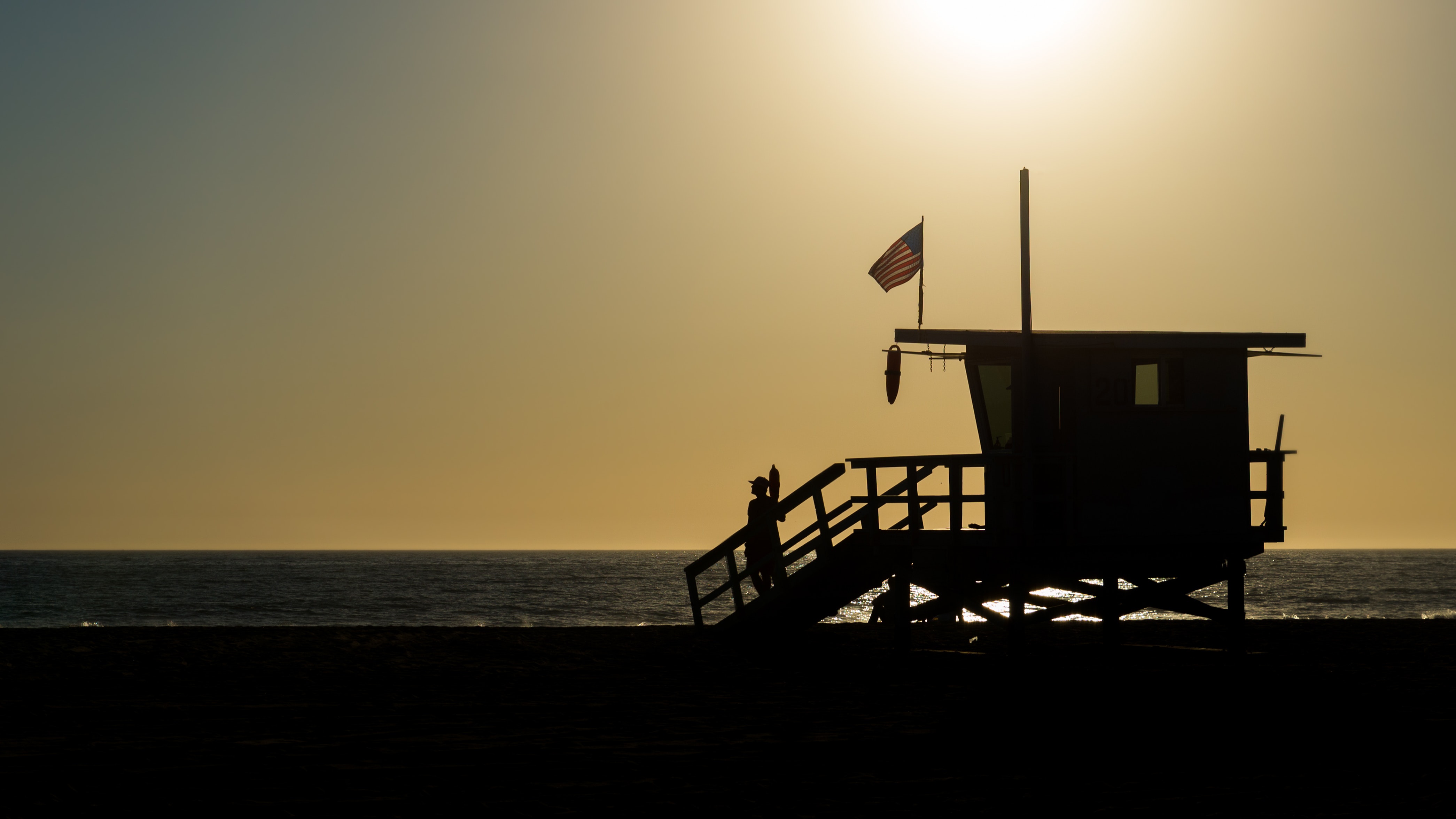 Silhouette of life guard house near ocean during sunset photo