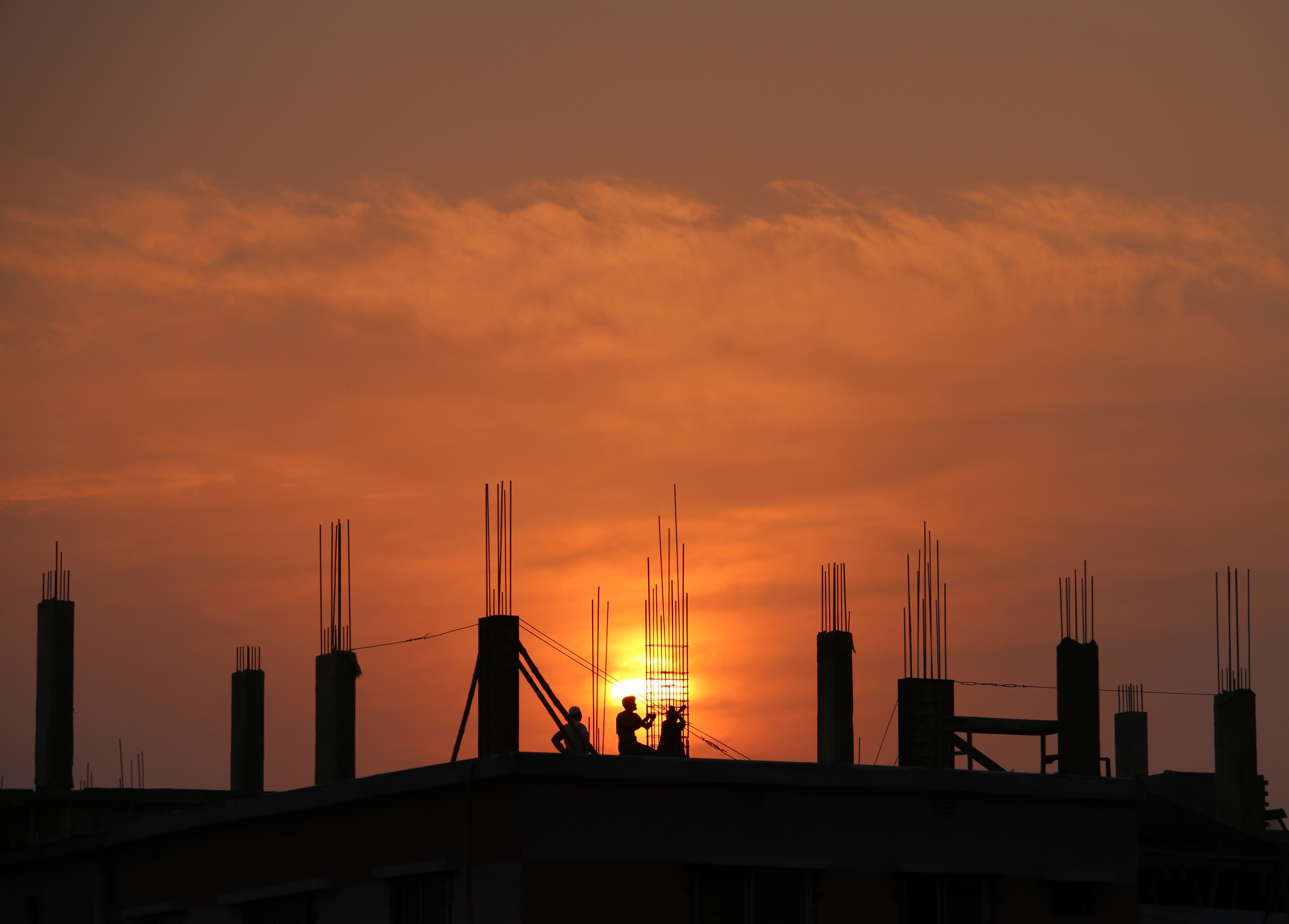 Silhouette of men in construction site during sunset photo