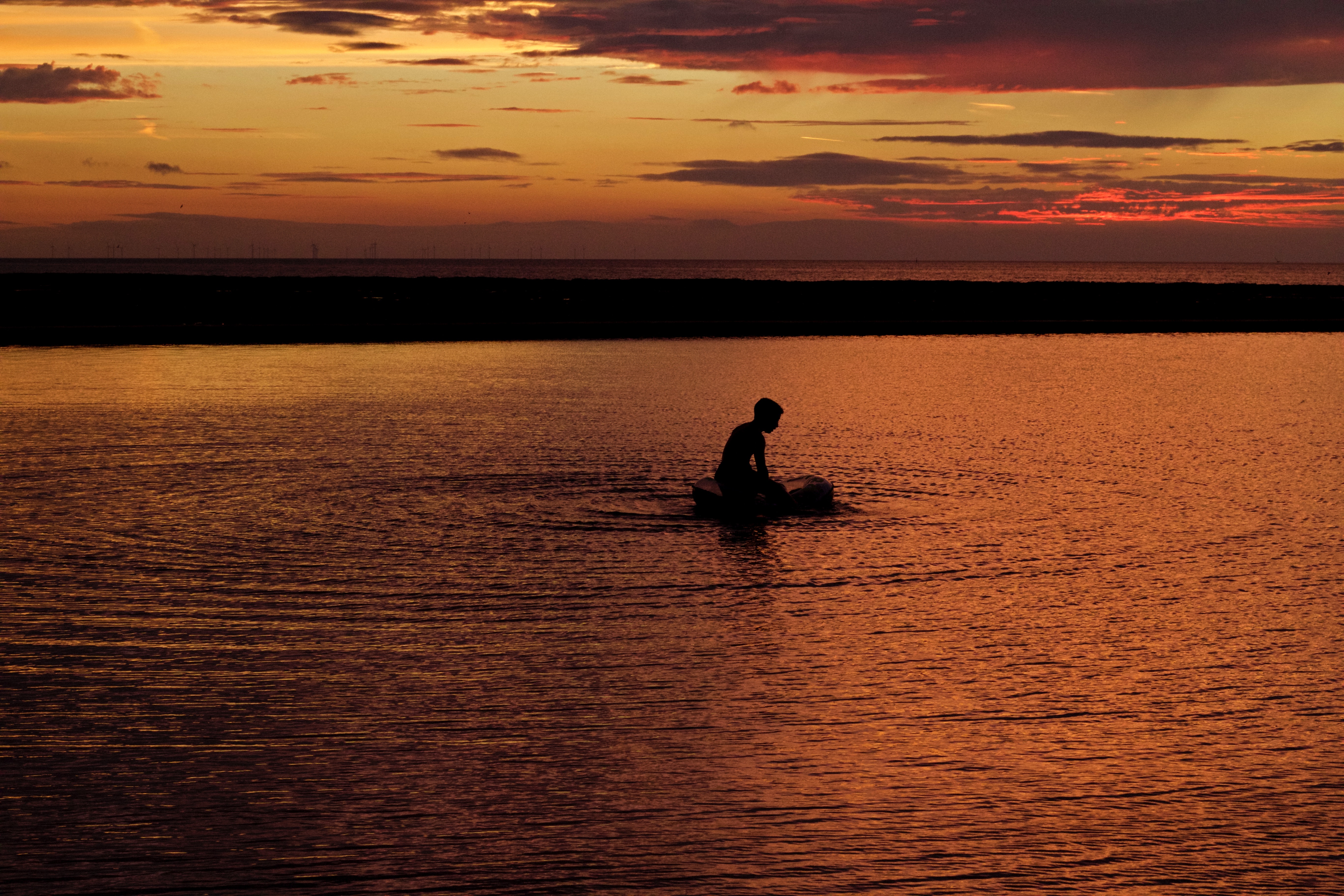 Silhouette of person on body of water during sunset photo