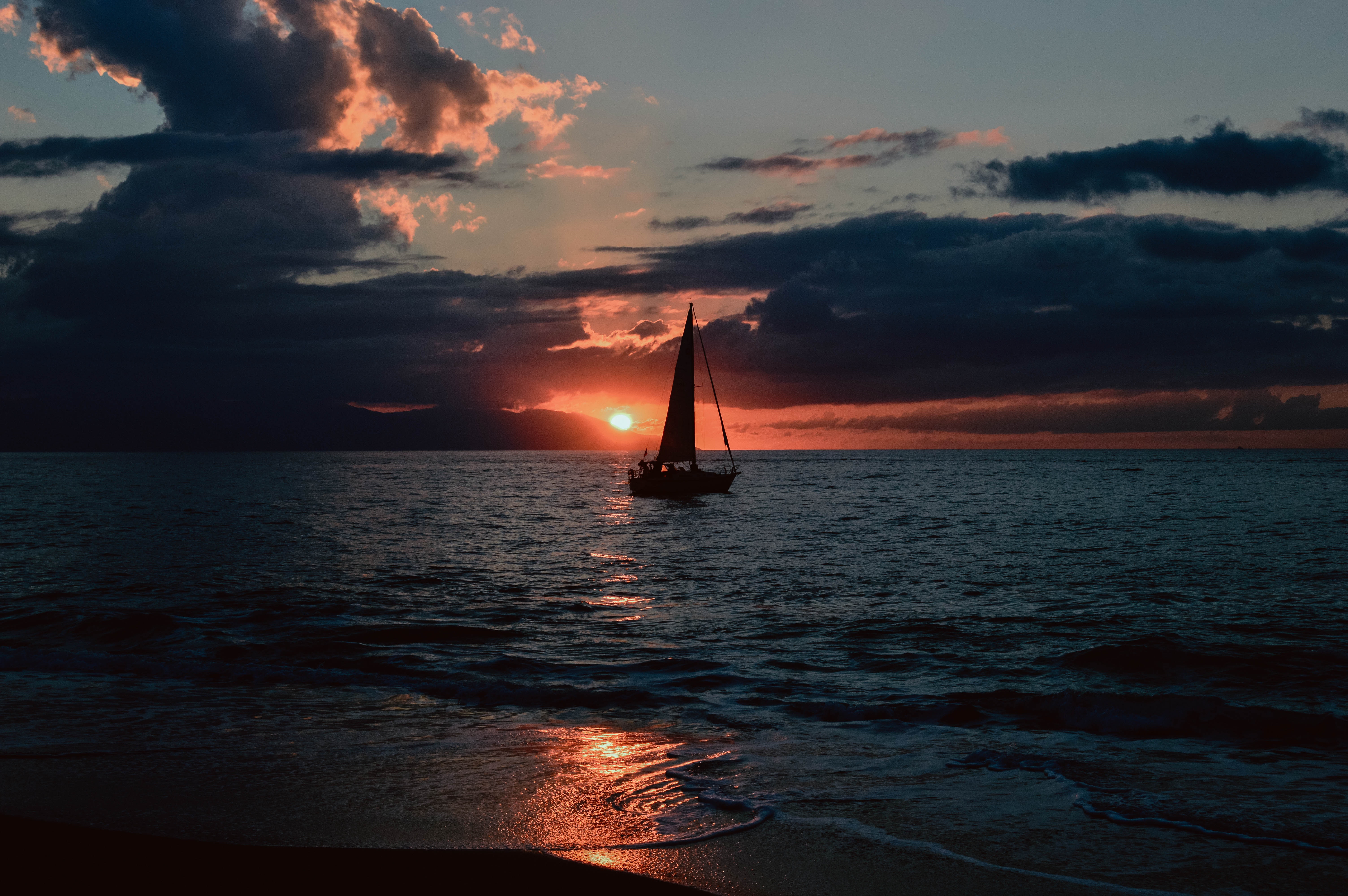 Silhouette of sailboat on body of water during sunset photo