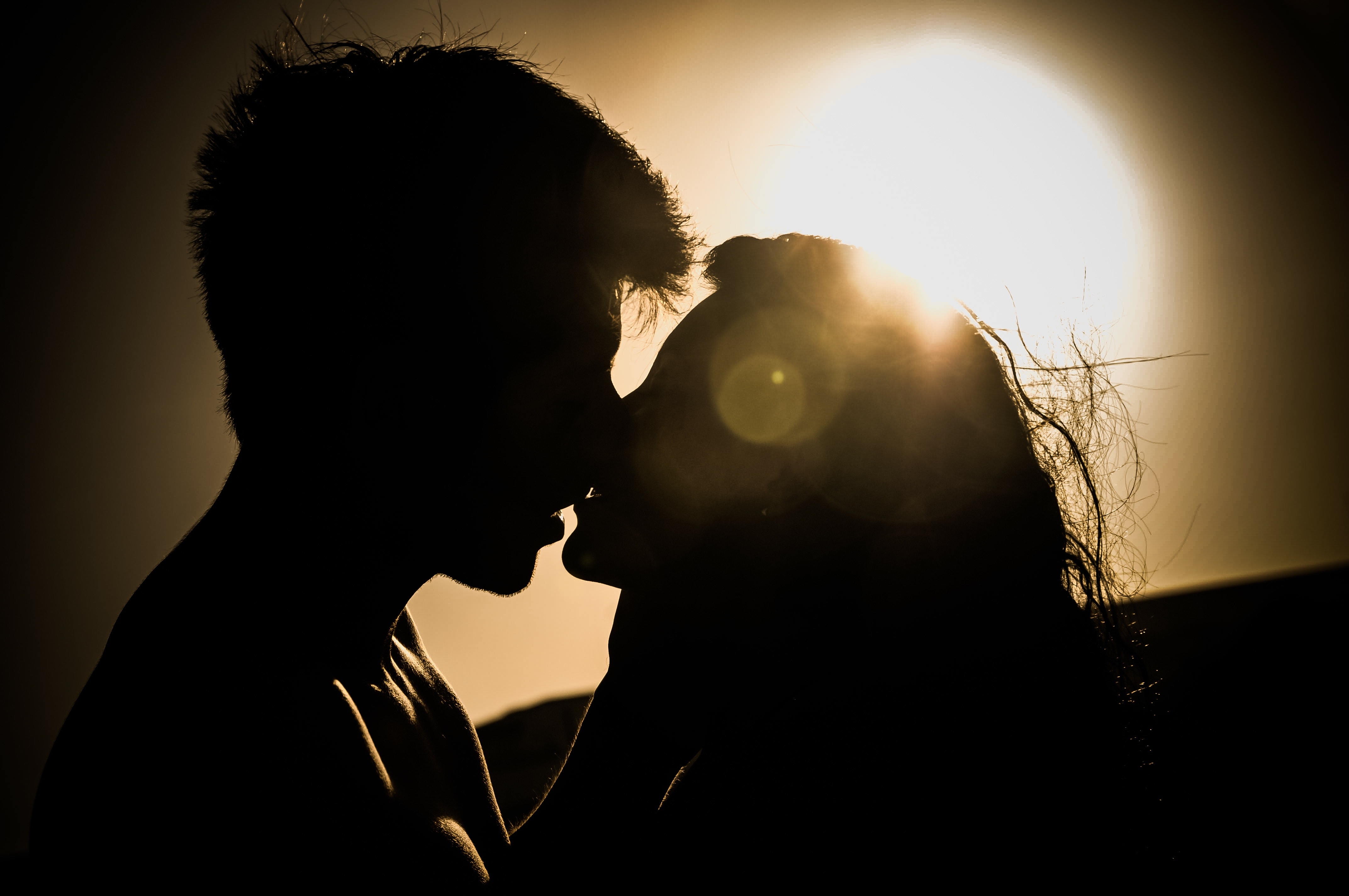 Silhouettes of couple kissing against sunset photo