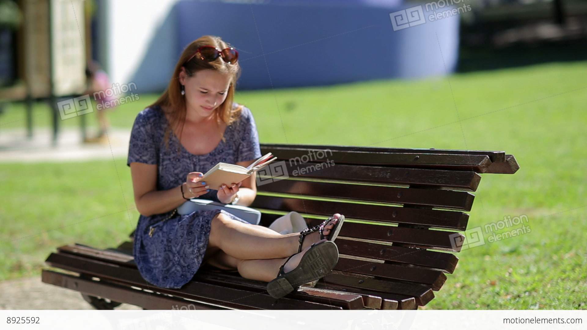 Young Woman Relaxing, Reading A Book And Sitting On A Bench With ...