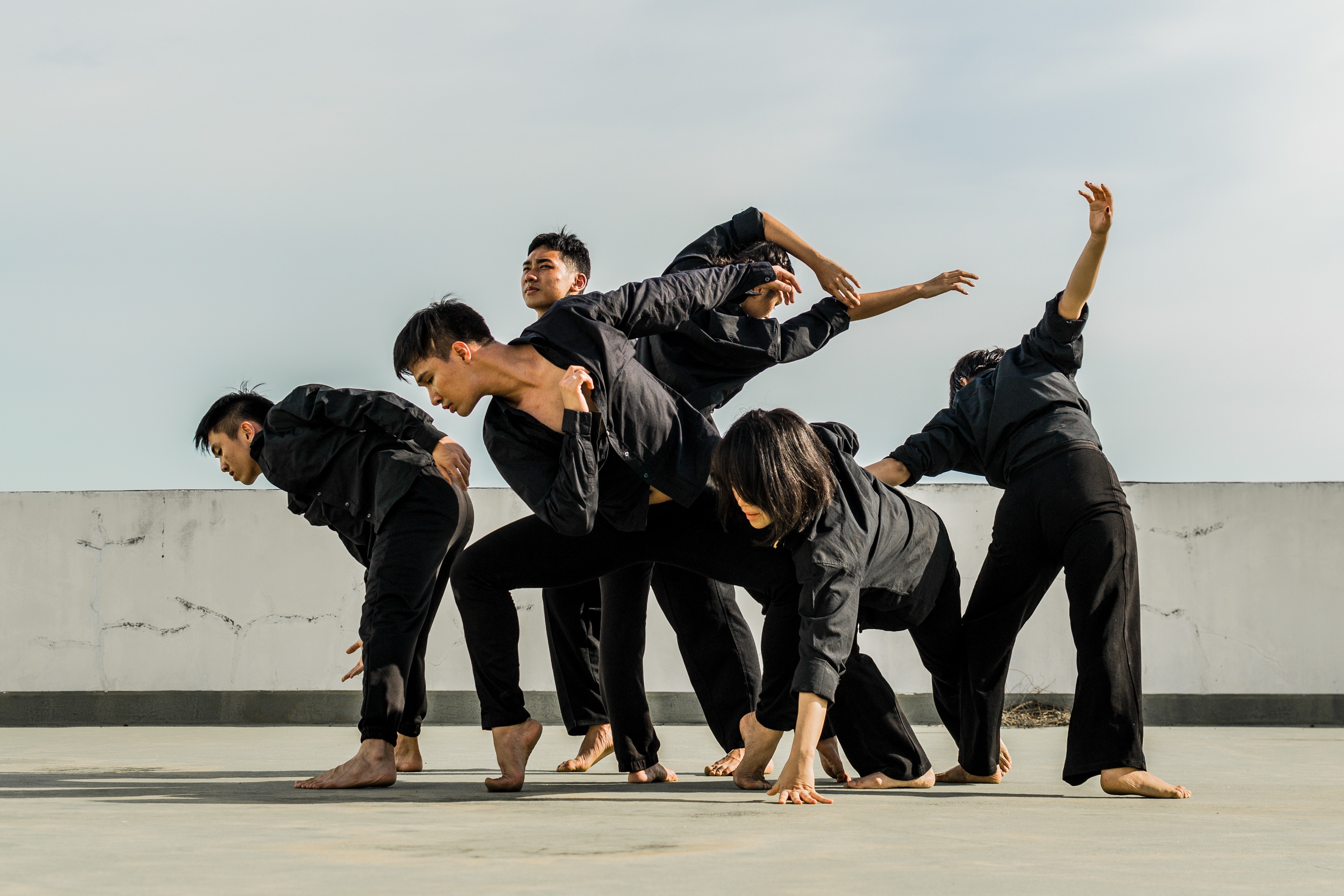 Six people in black matching clothes dancing at daytime photo