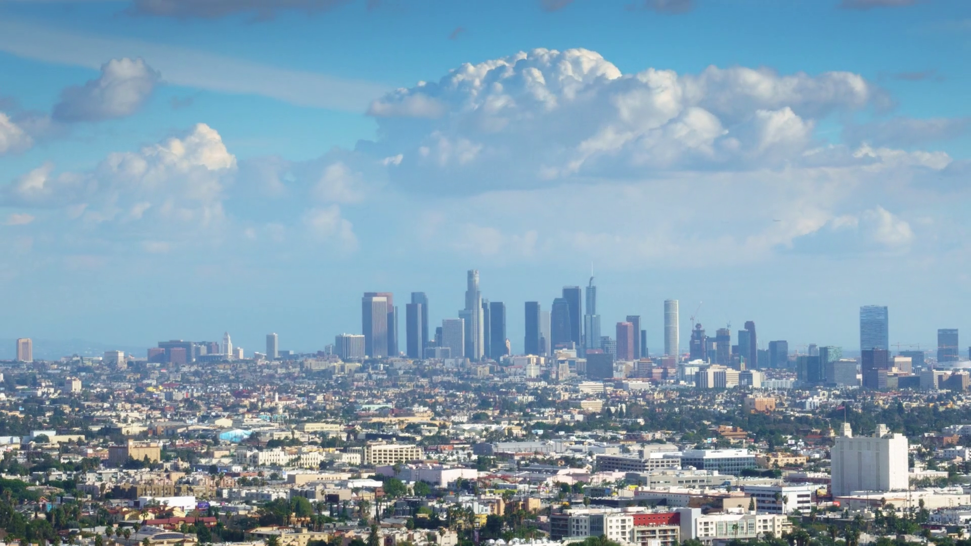 White clouds in blue sky over city of Los Angeles cityscape. Zoom ...