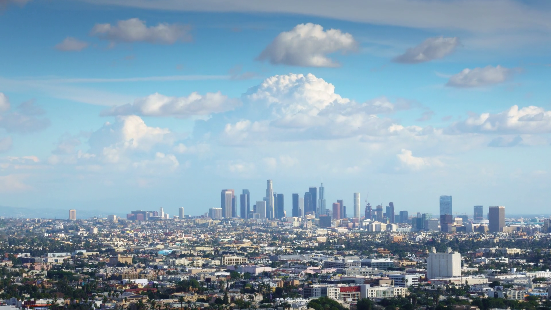 White clouds in blue sky over city of Los Angeles cityscape. Zoom in ...