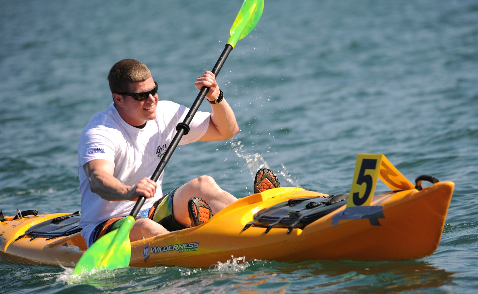 Smiling man in white crew neck t shirt wearing sunglasses paddling on yellow kayak during daytime photo