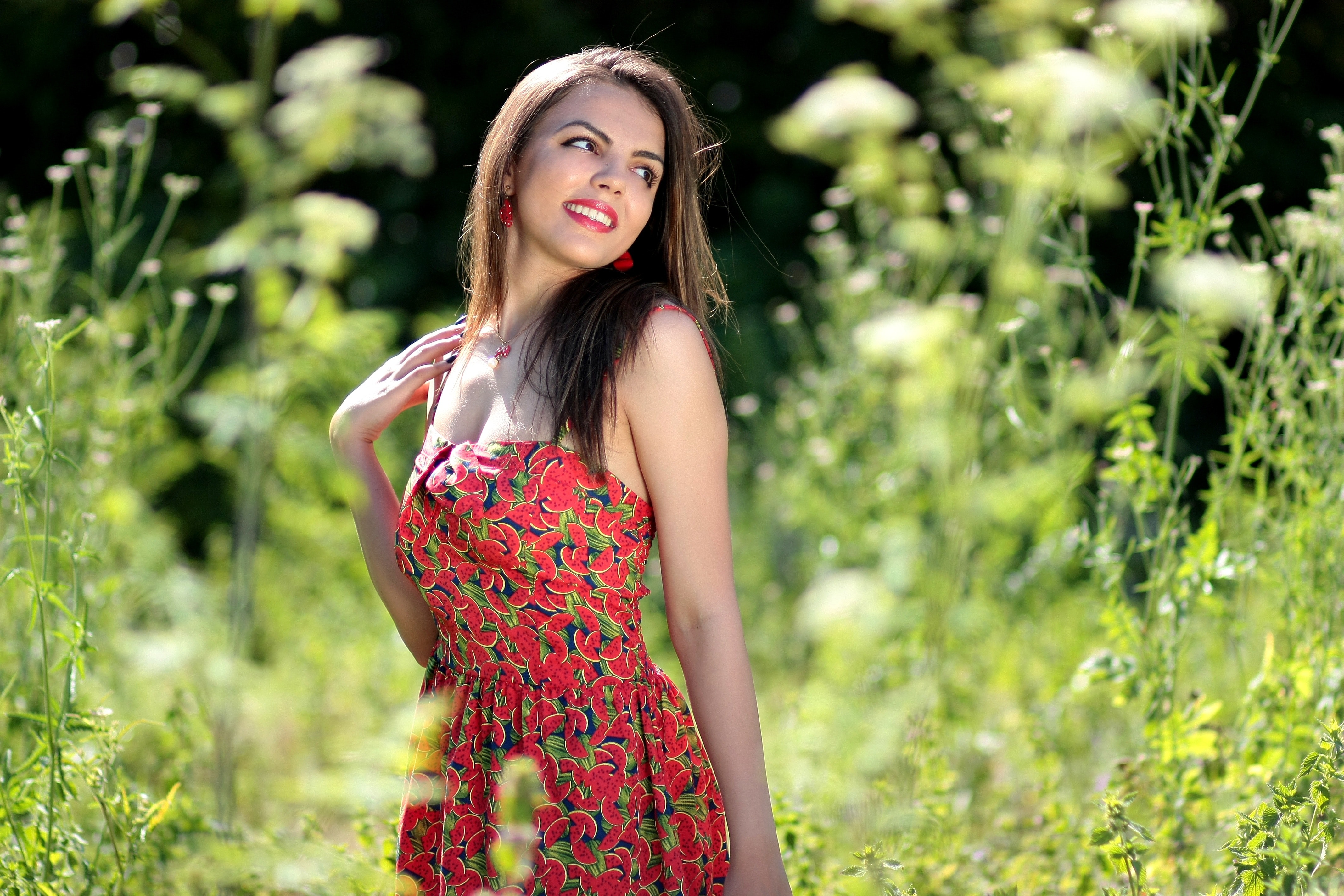 Smiling woman in pink black and green floral tube dress near green leaf plants during daytime photo