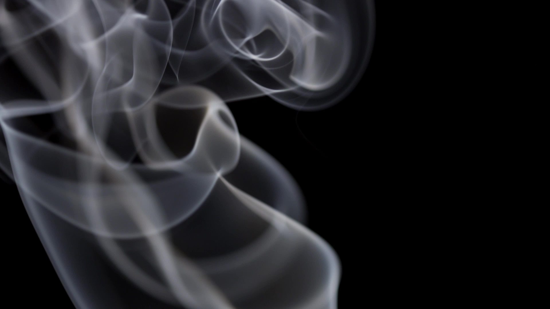 Hypnotic swirls and spirals created by white smoke floating and ...