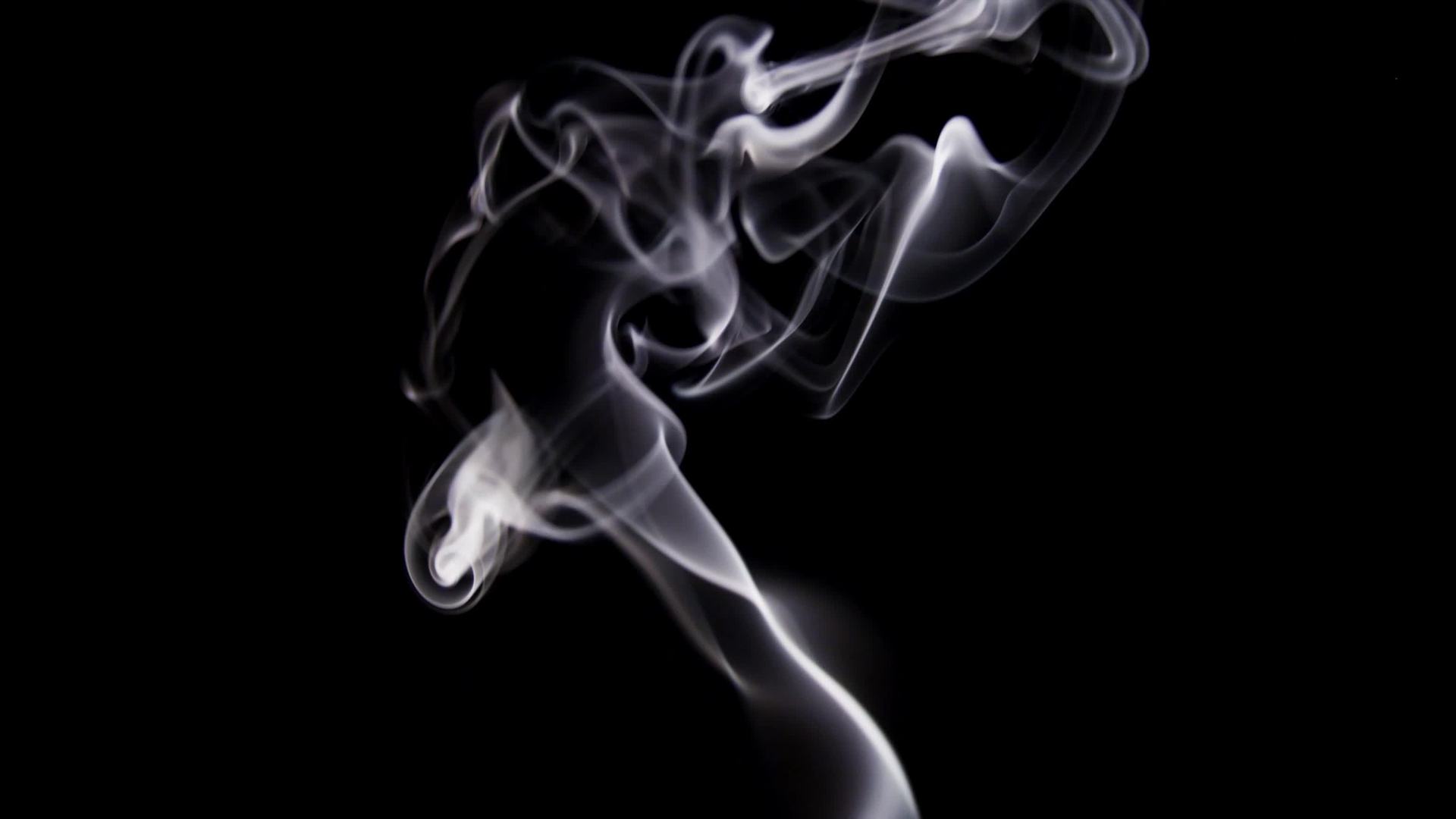 Thin lines of white smoke drawing swirls and waves on dark ...