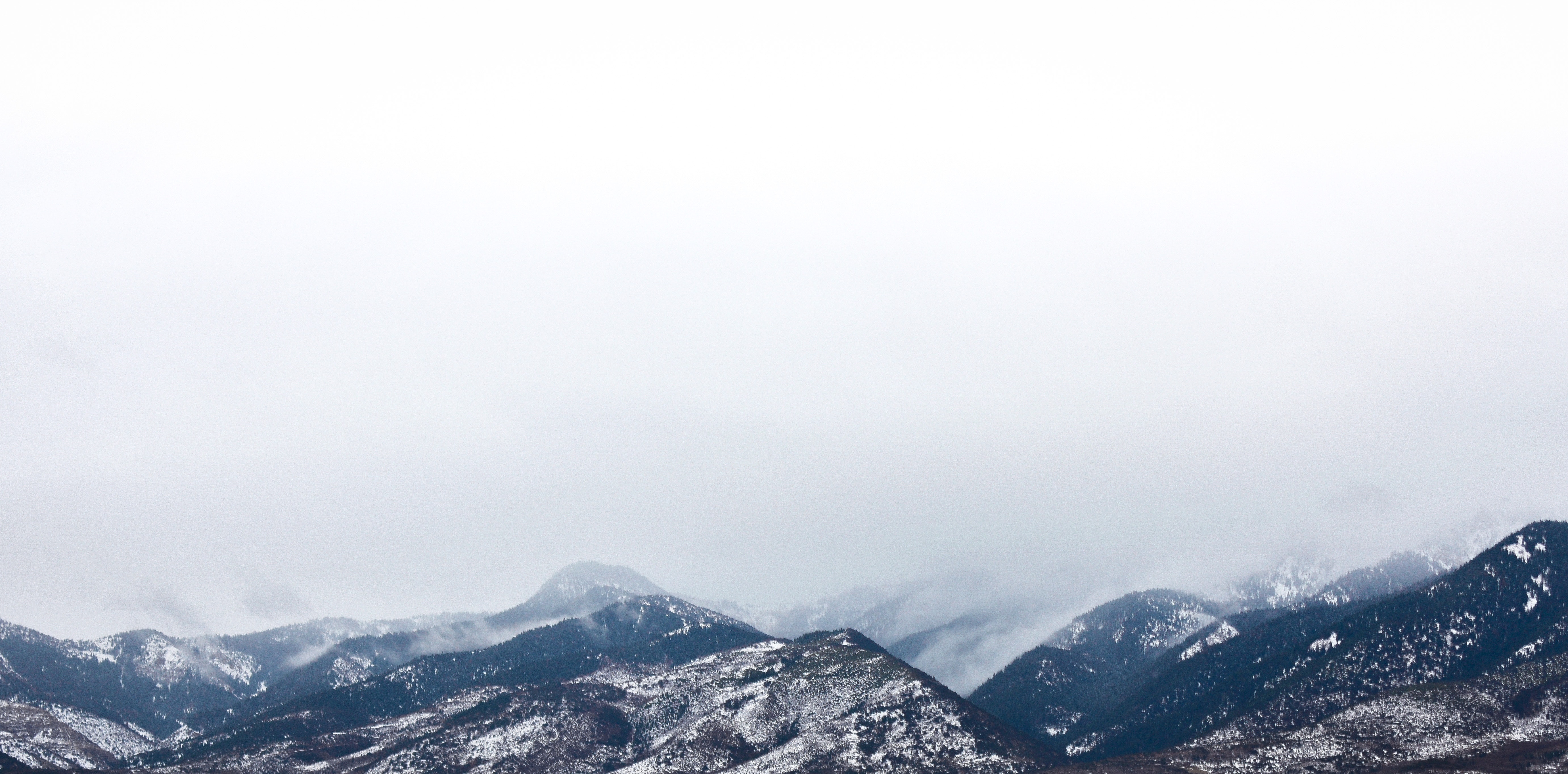 Snow coated mountain under white clouds photo