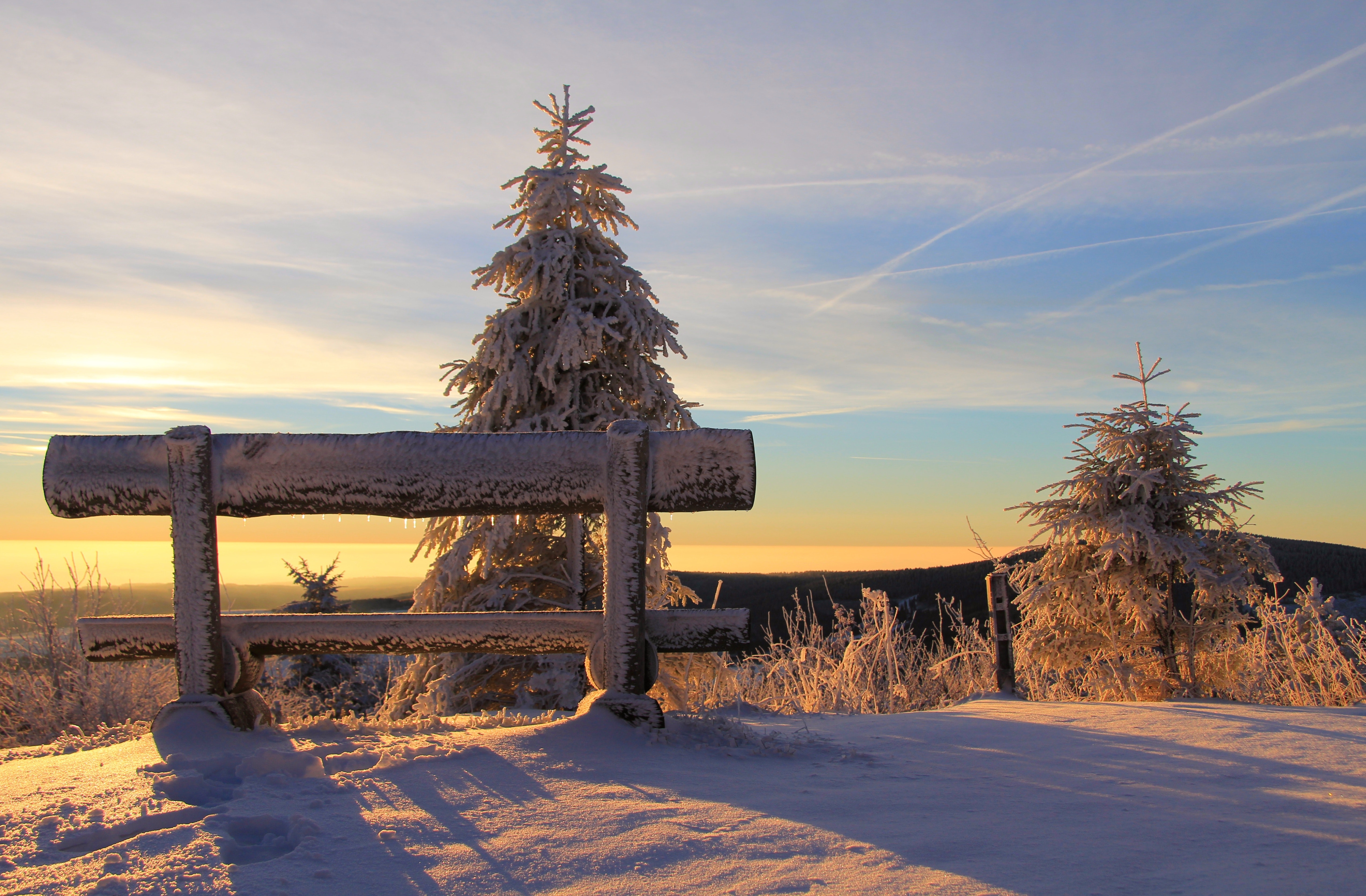 Snow covered bench on mountain top during sunset photo