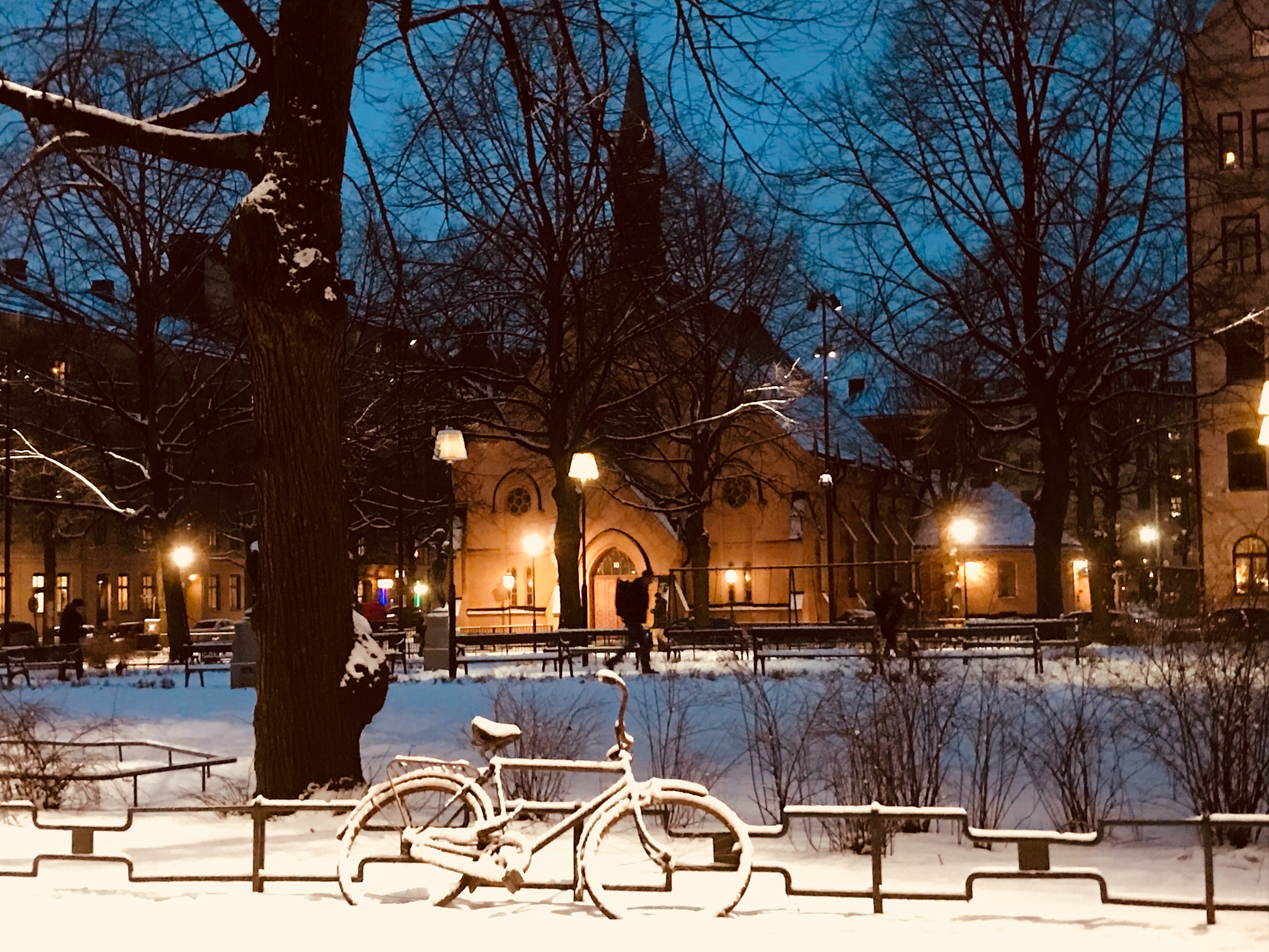 Snow covered bike near fence during nighttime photo