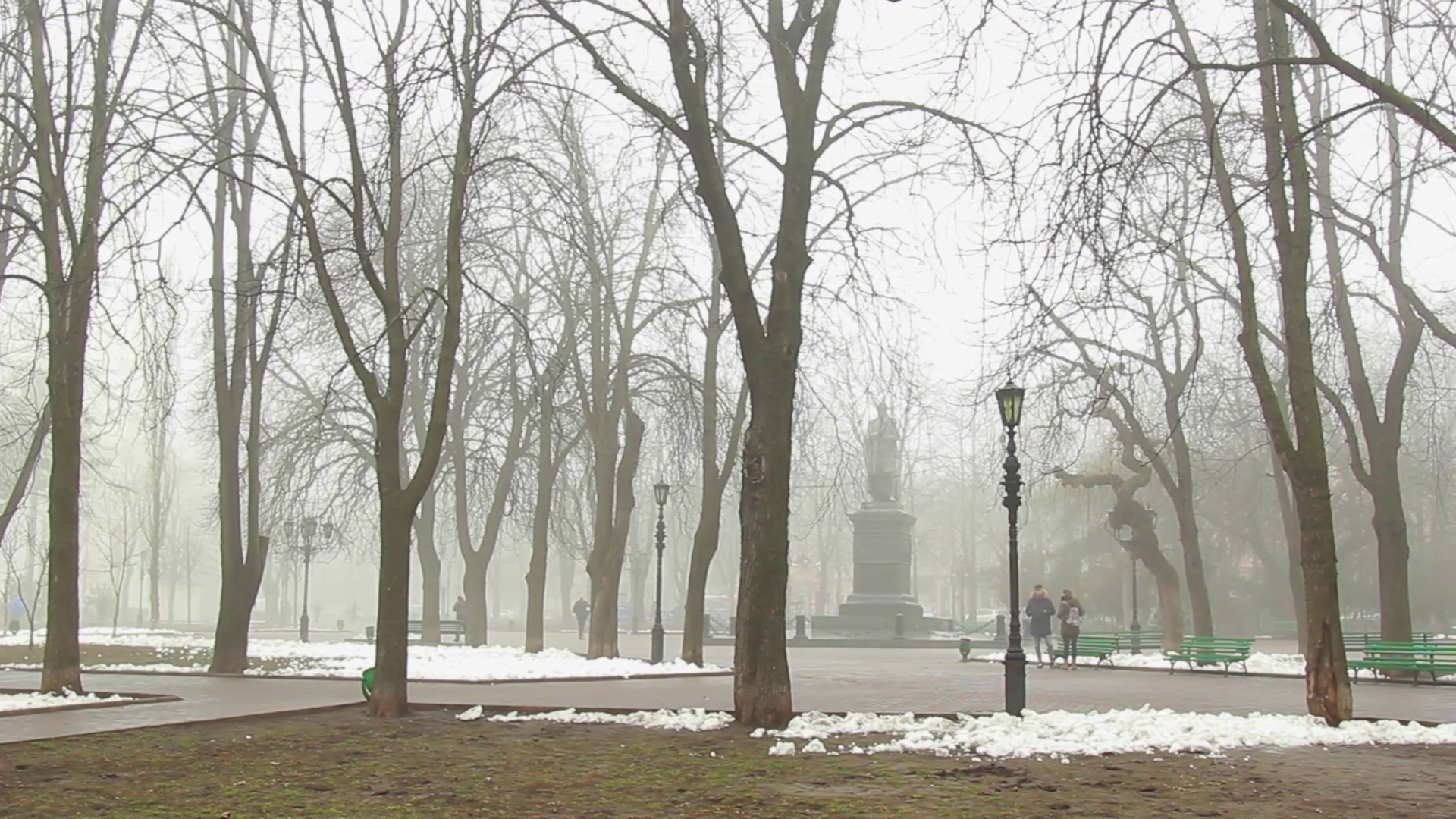 People walking at a snowy town square on a foggy winter day in ...