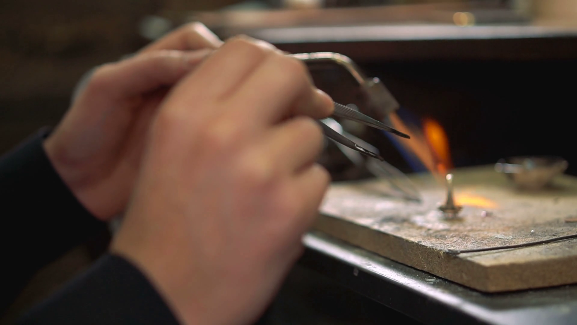 Process annealing a silver ring using a soldering iron in his hand ...