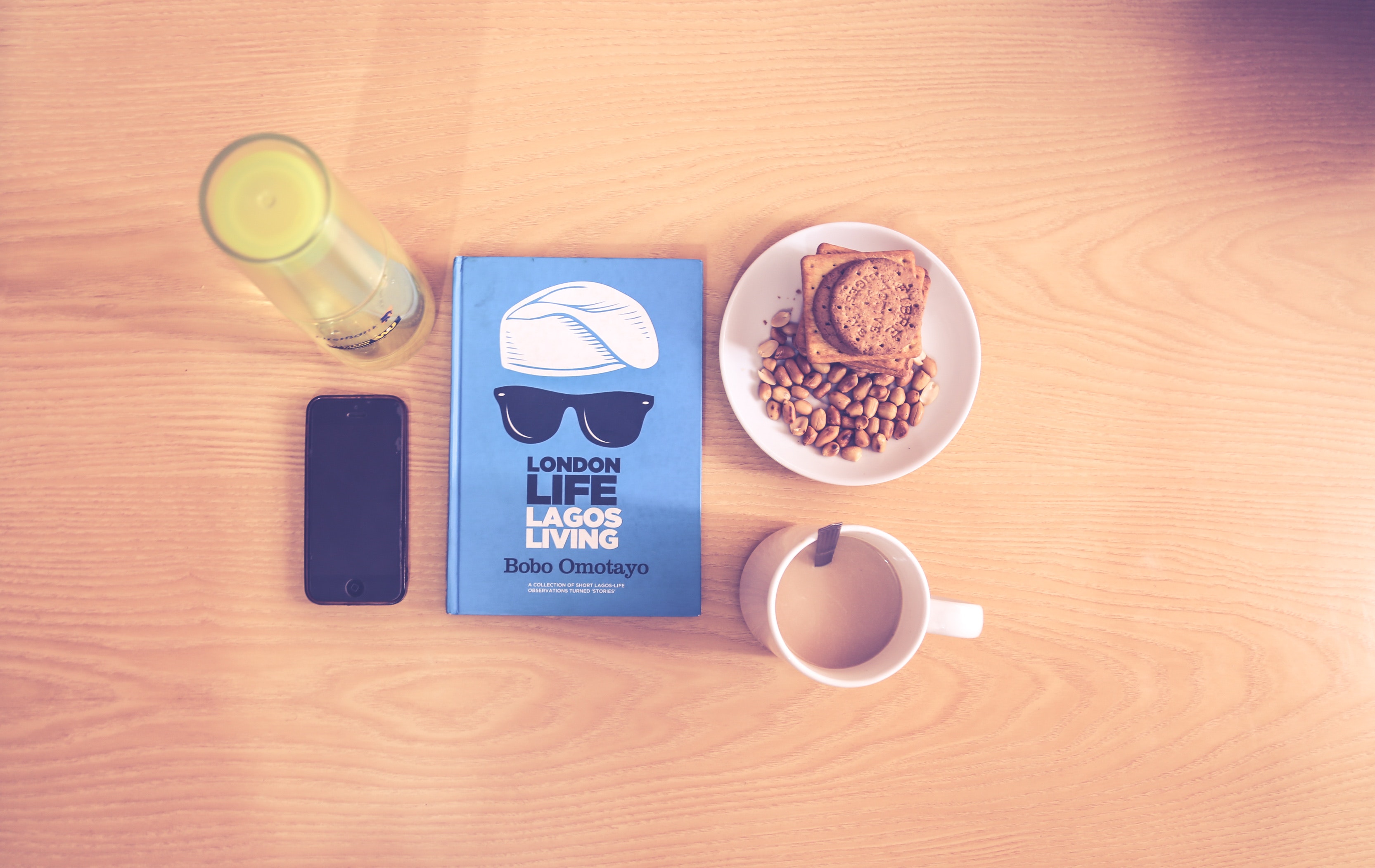Space gray iphone beside blue labeled book near white ceramic cup with liquid content photo