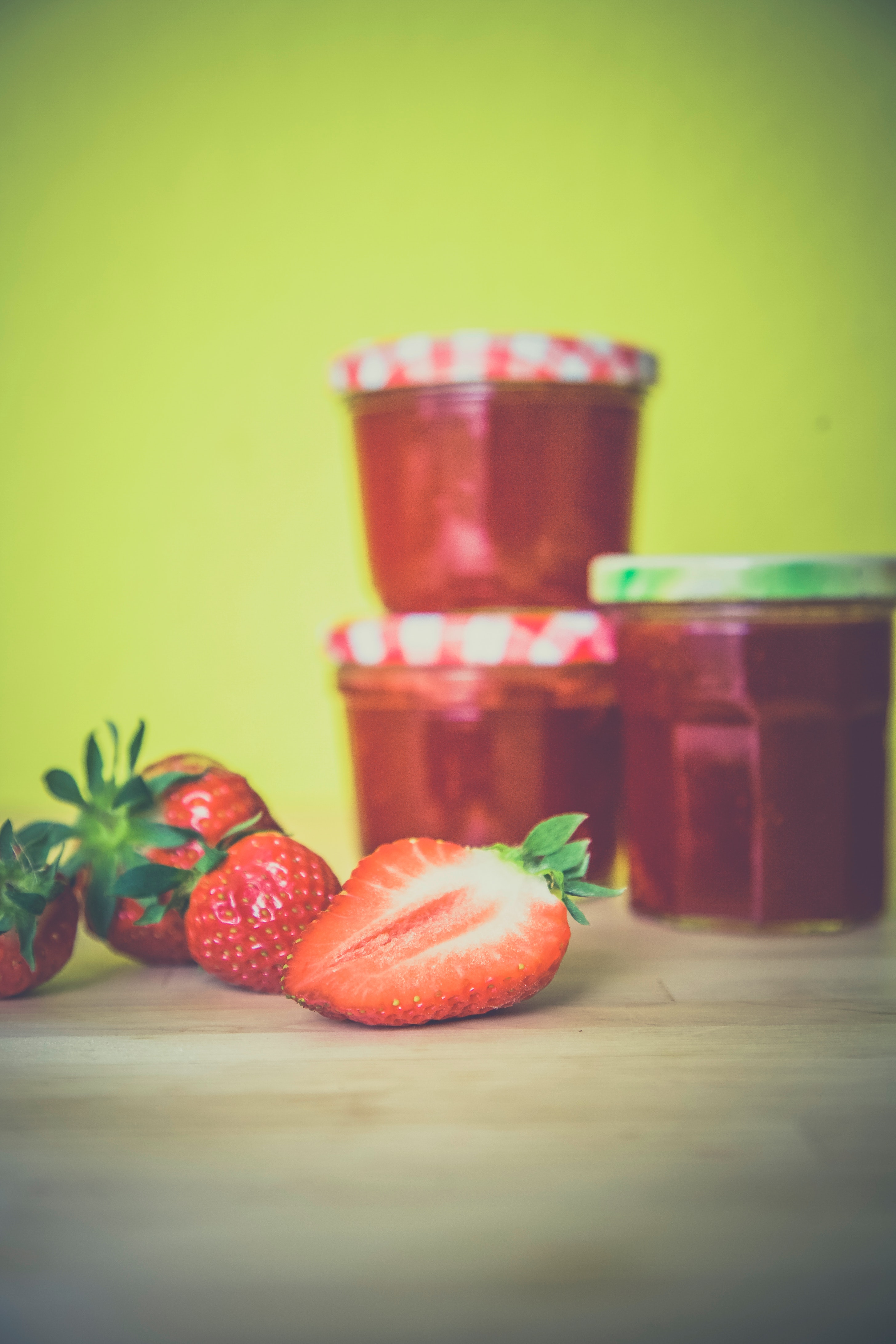 Strawberry near red jar on wooden surface photo